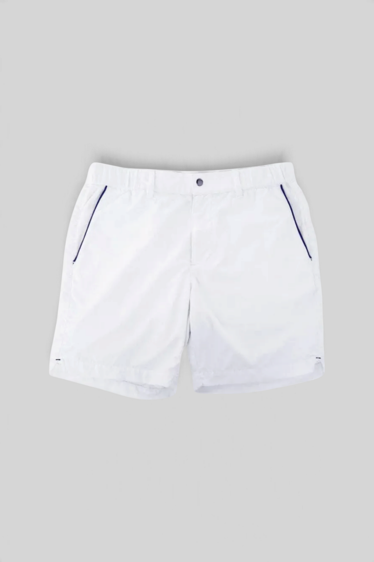 The Copper Shed white Court Shorts with elastic waistband, 7-inch inseam, and navy blue piping detail on pockets.
