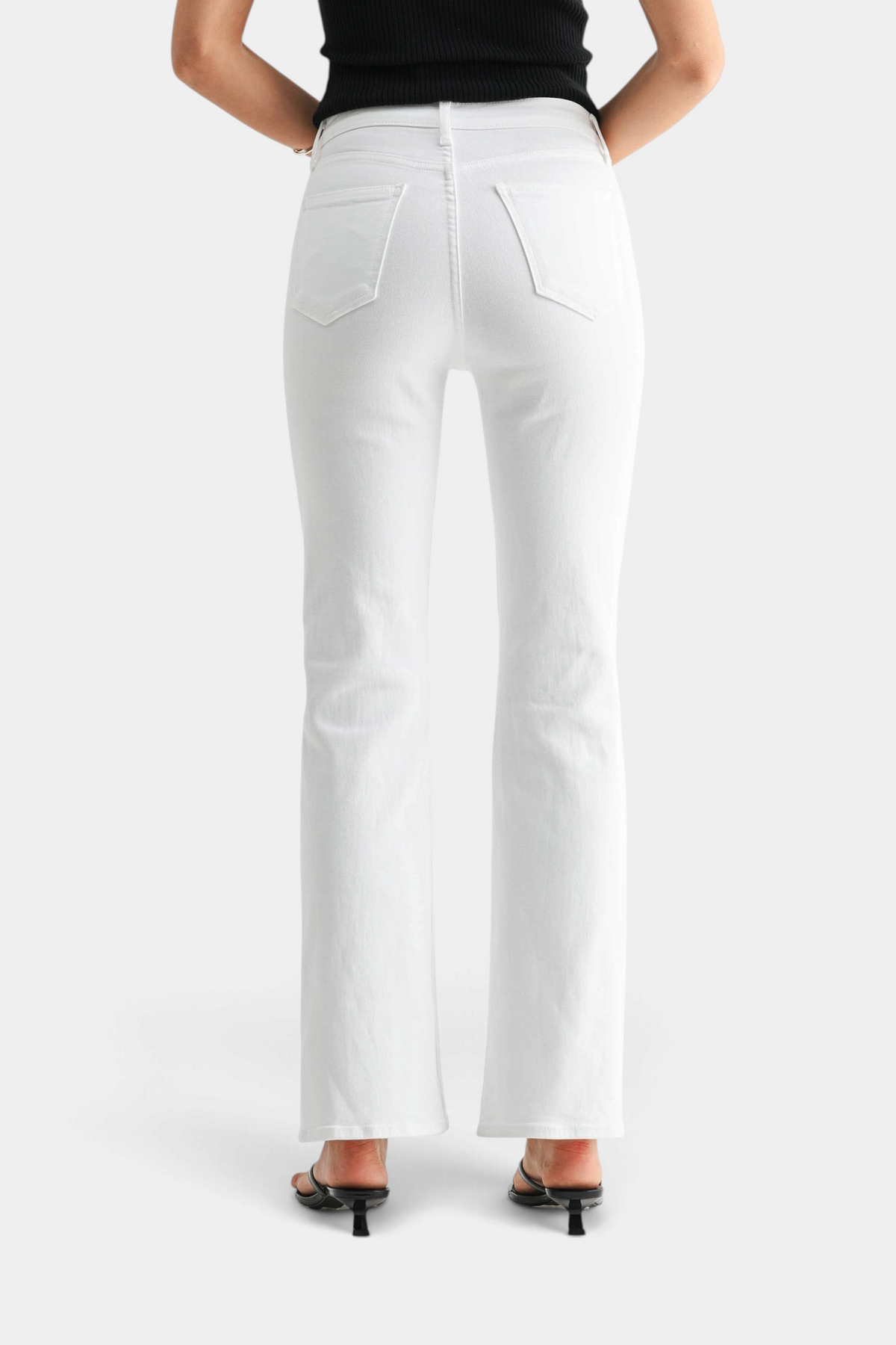 The Copper Shed high-rise white denim jeans with a relaxed fit and flared hem, back view on a model.