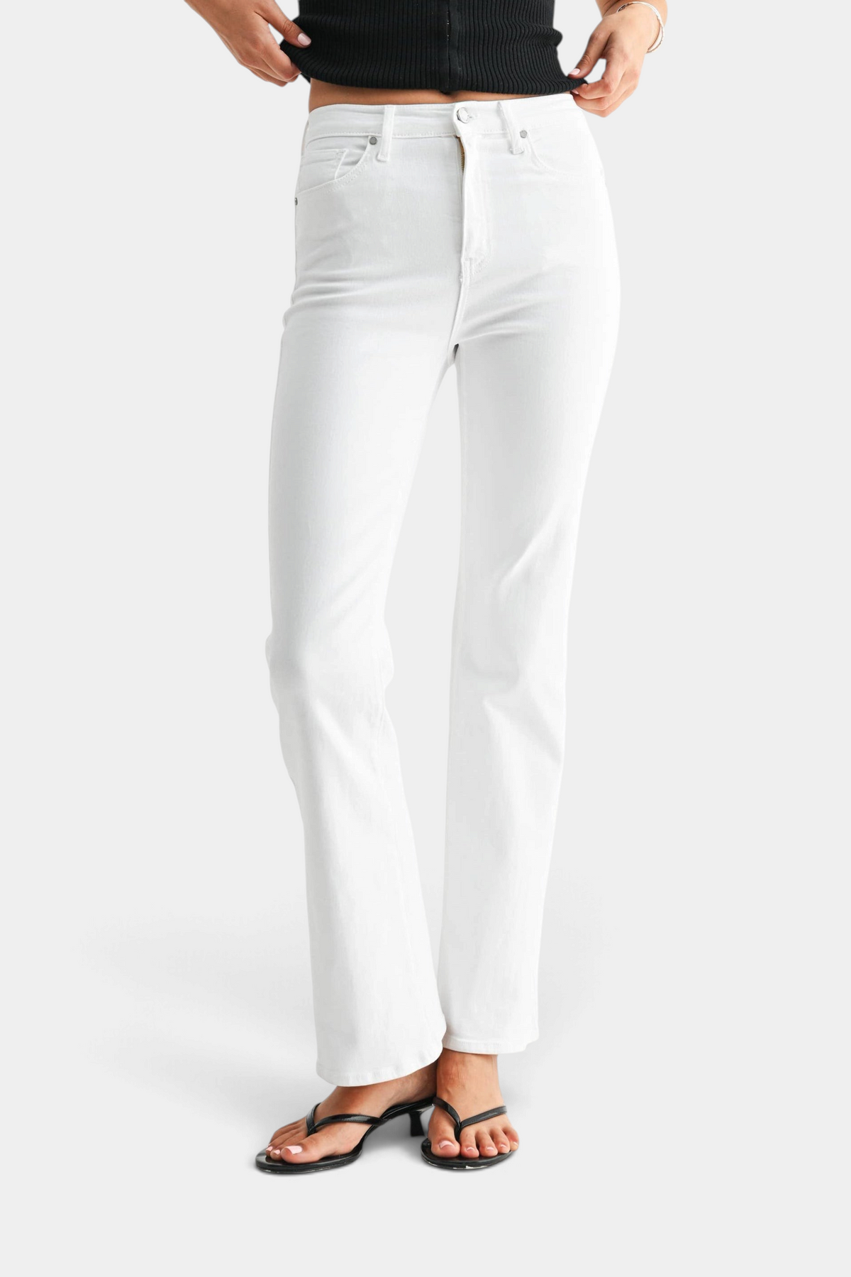 The Copper Shed optic white high-rise relaxed skinny flare denim jeans worn with black sandals on a white background.
