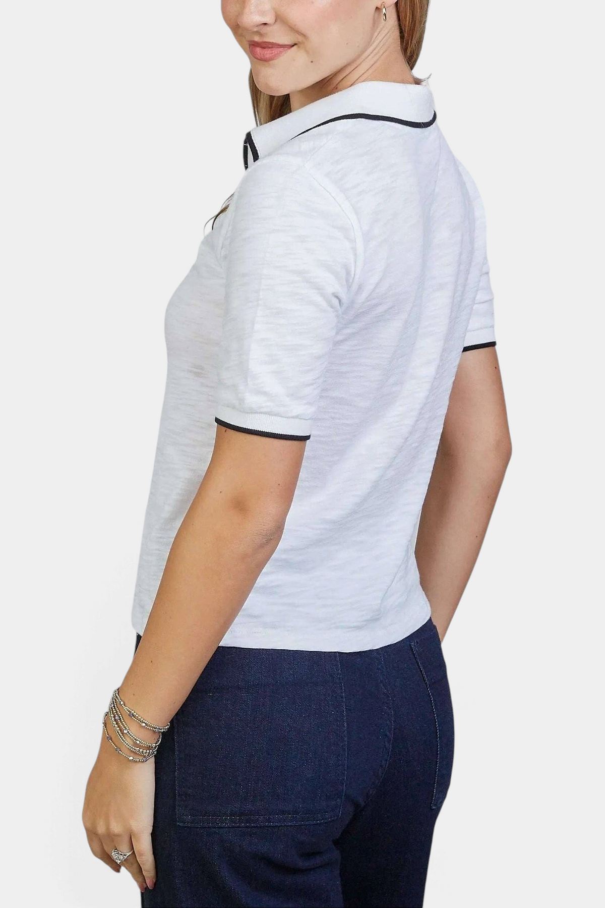 The Copper Shed white Pima cotton polo shirt with black contrast piping on collar and sleeves worn by a woman