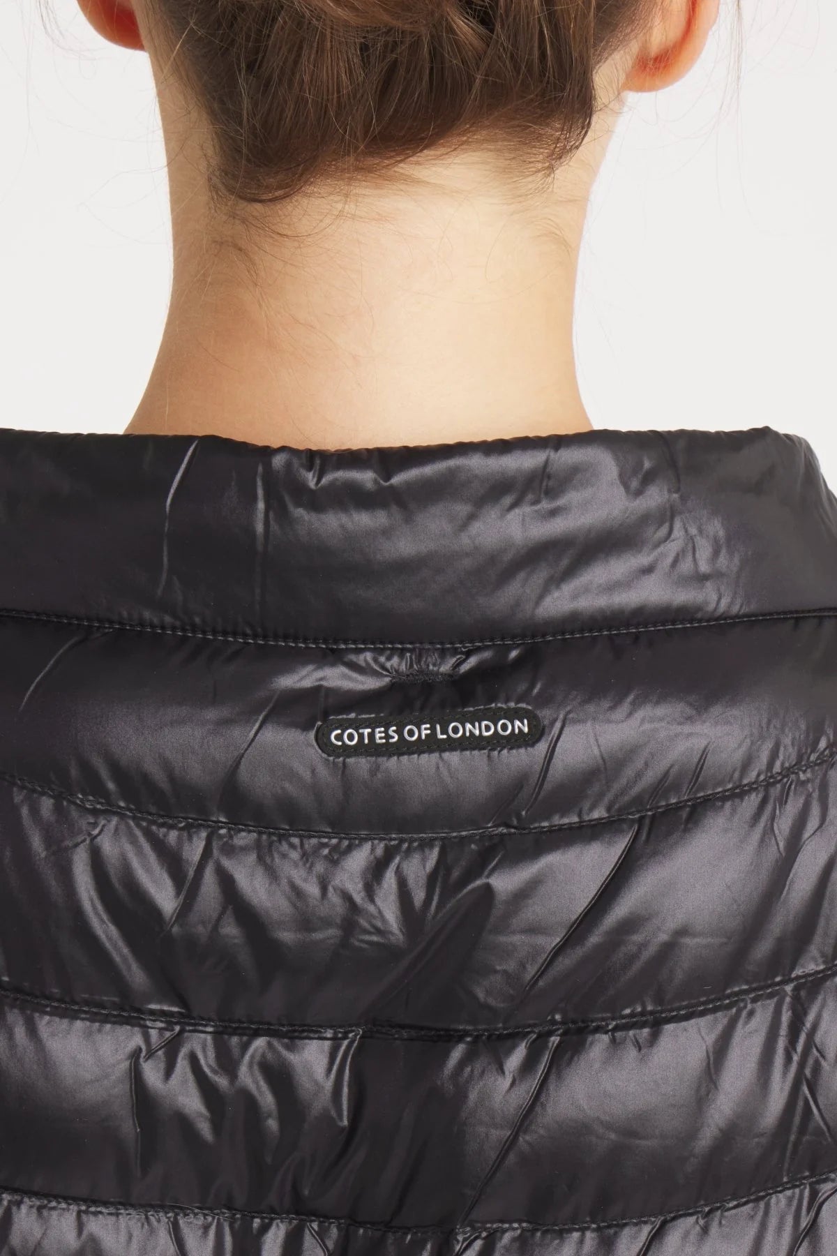 Black puffer jacket with 'Cotes of London' label on a white background