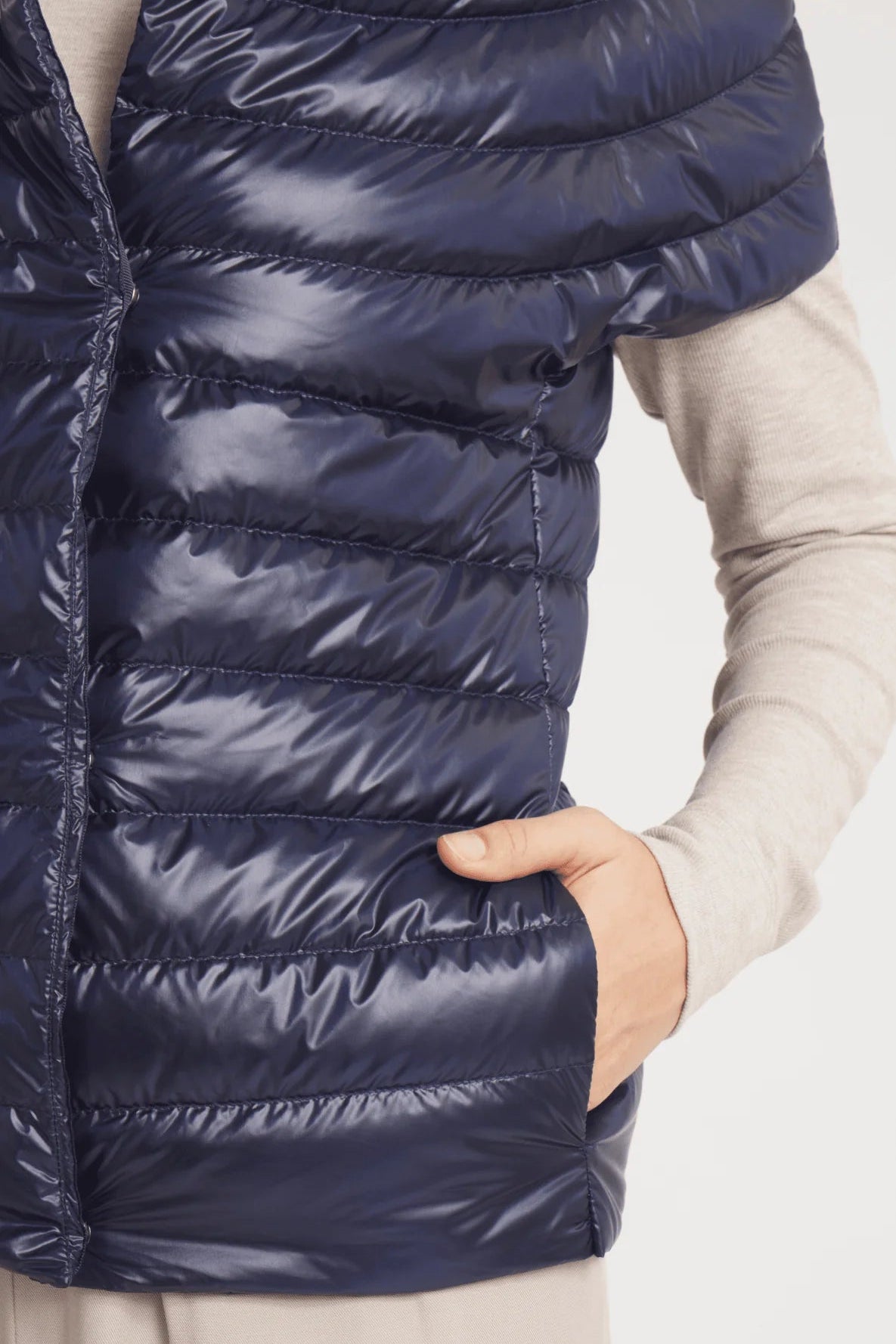 Navy puffer vest worn by a person on a light gray background