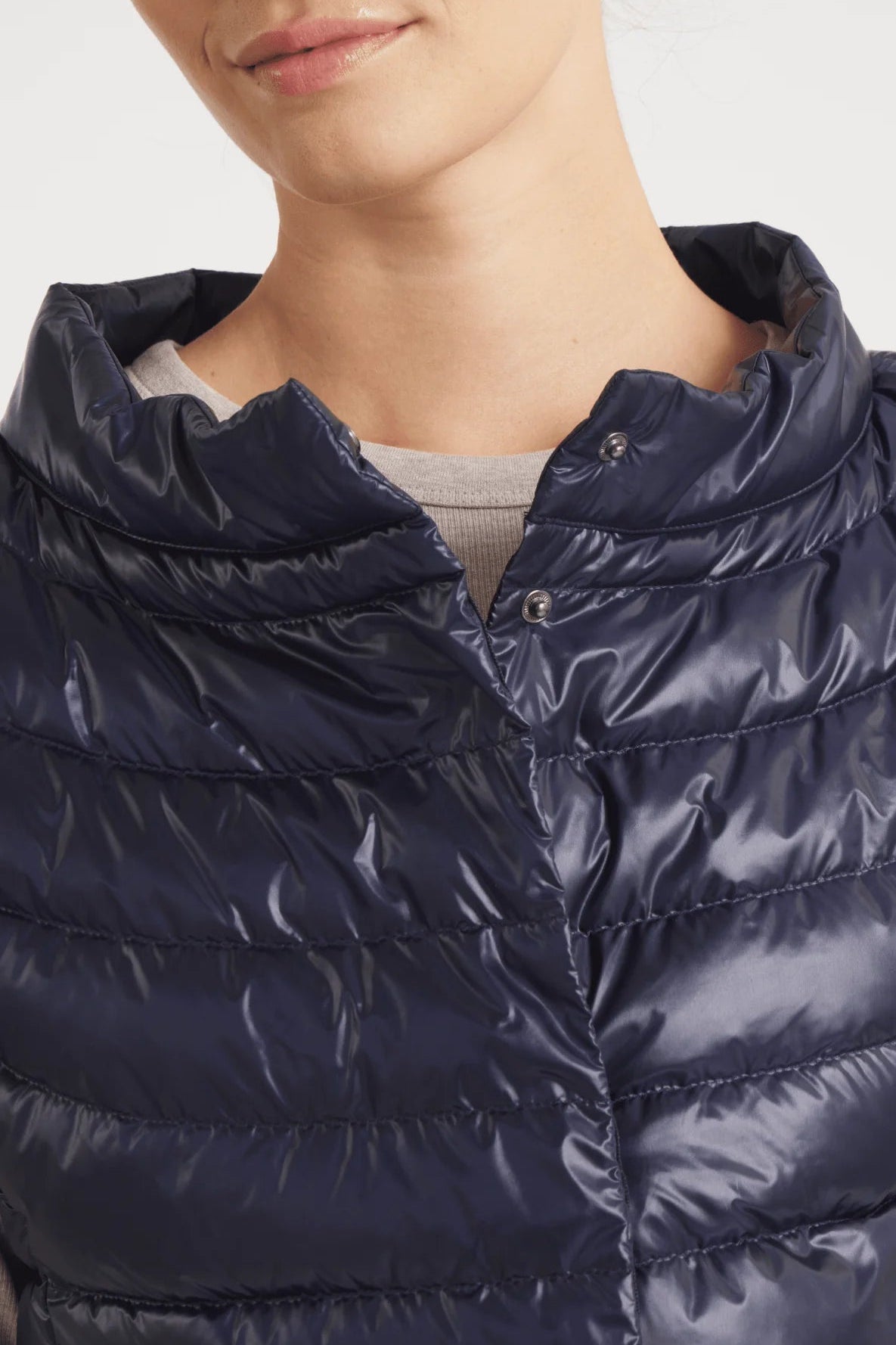 Navy blue puffer jacket worn by a person on a light gray background
