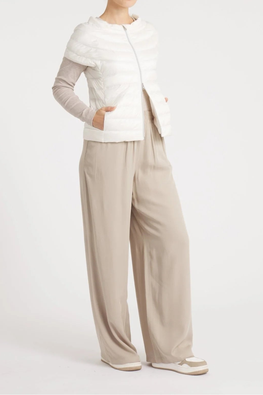 Woman wearing a white top and beige pants on a white background