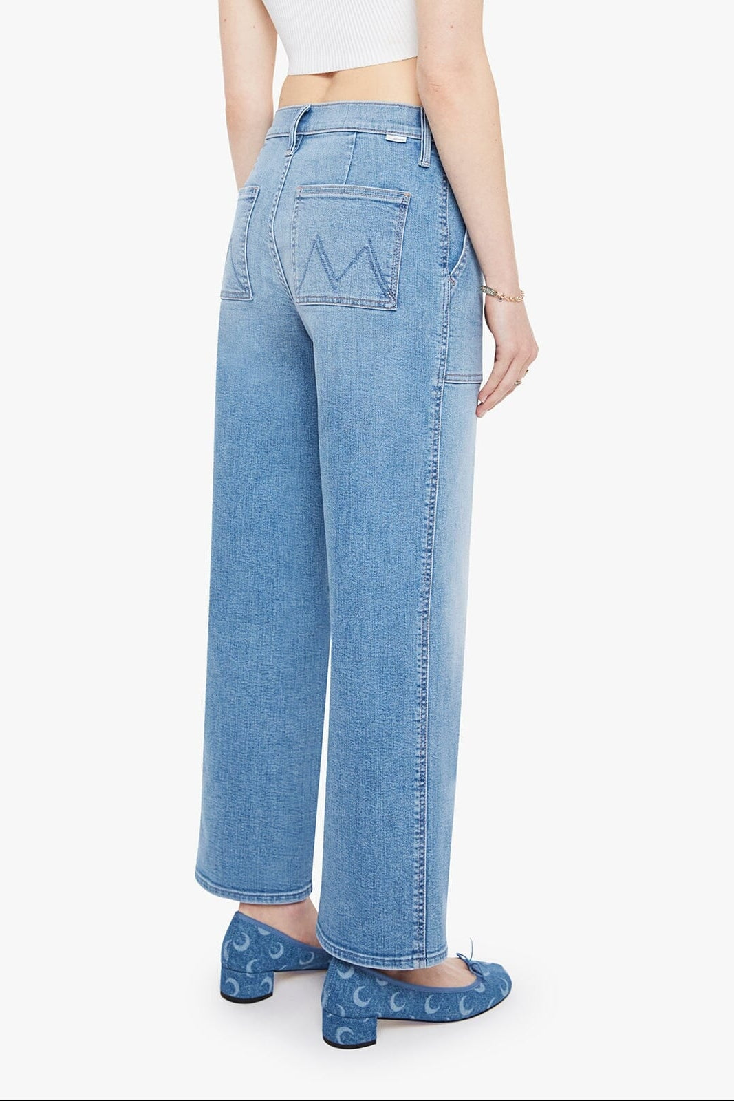 Person wearing light blue jeans and a white top on a white background