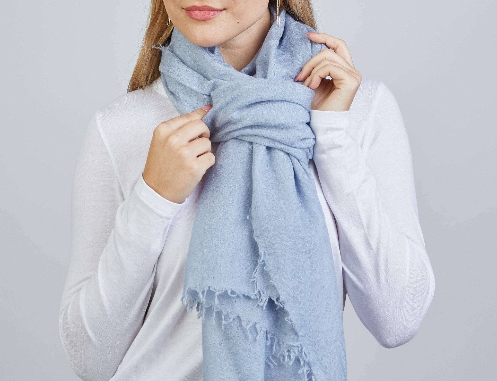 Woman wearing a light blue scarf against a plain background