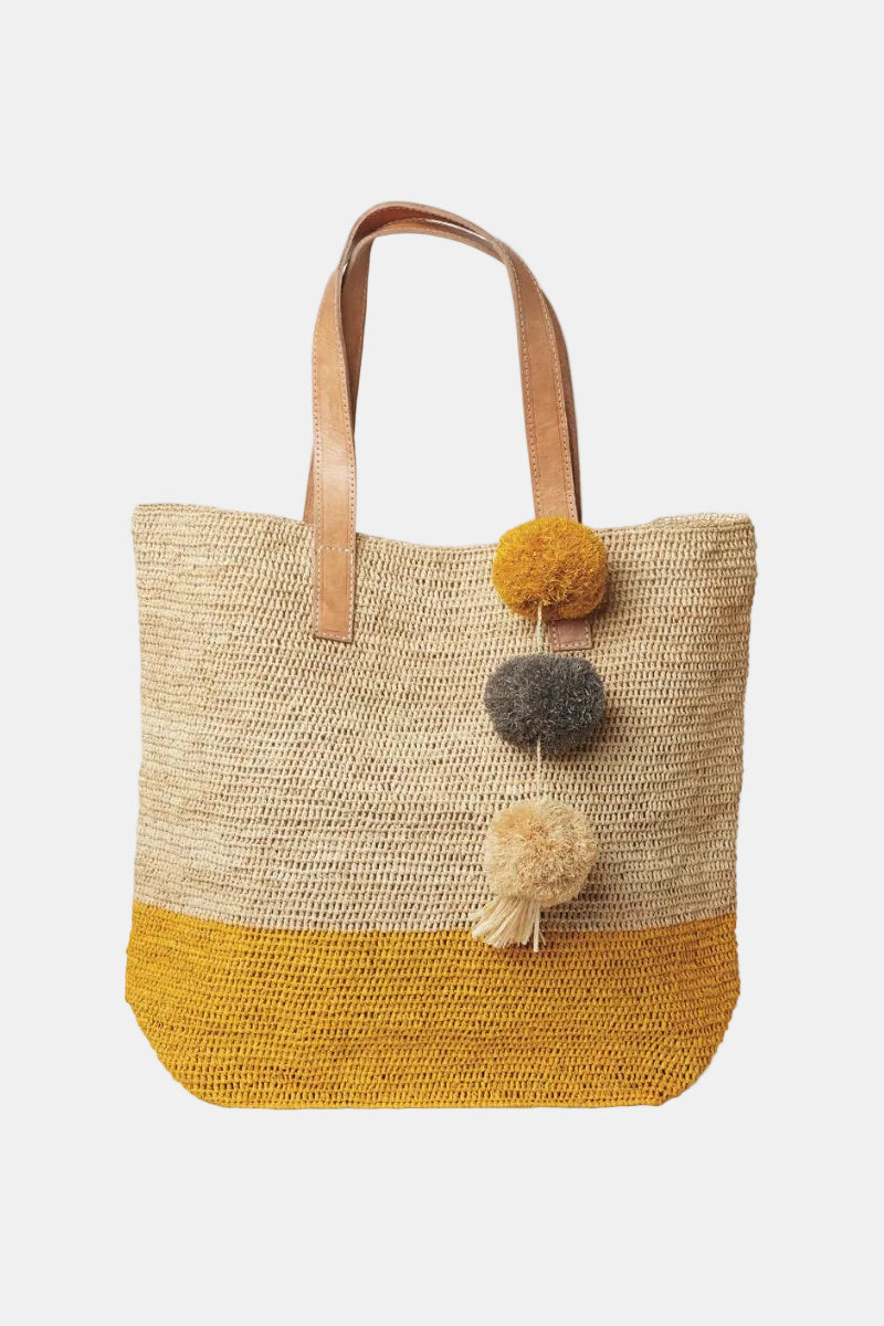 Woven tote bag with pom-poms on a white background