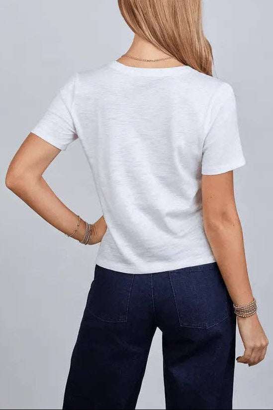 Person wearing a plain white t-shirt and dark pants on a light gray background