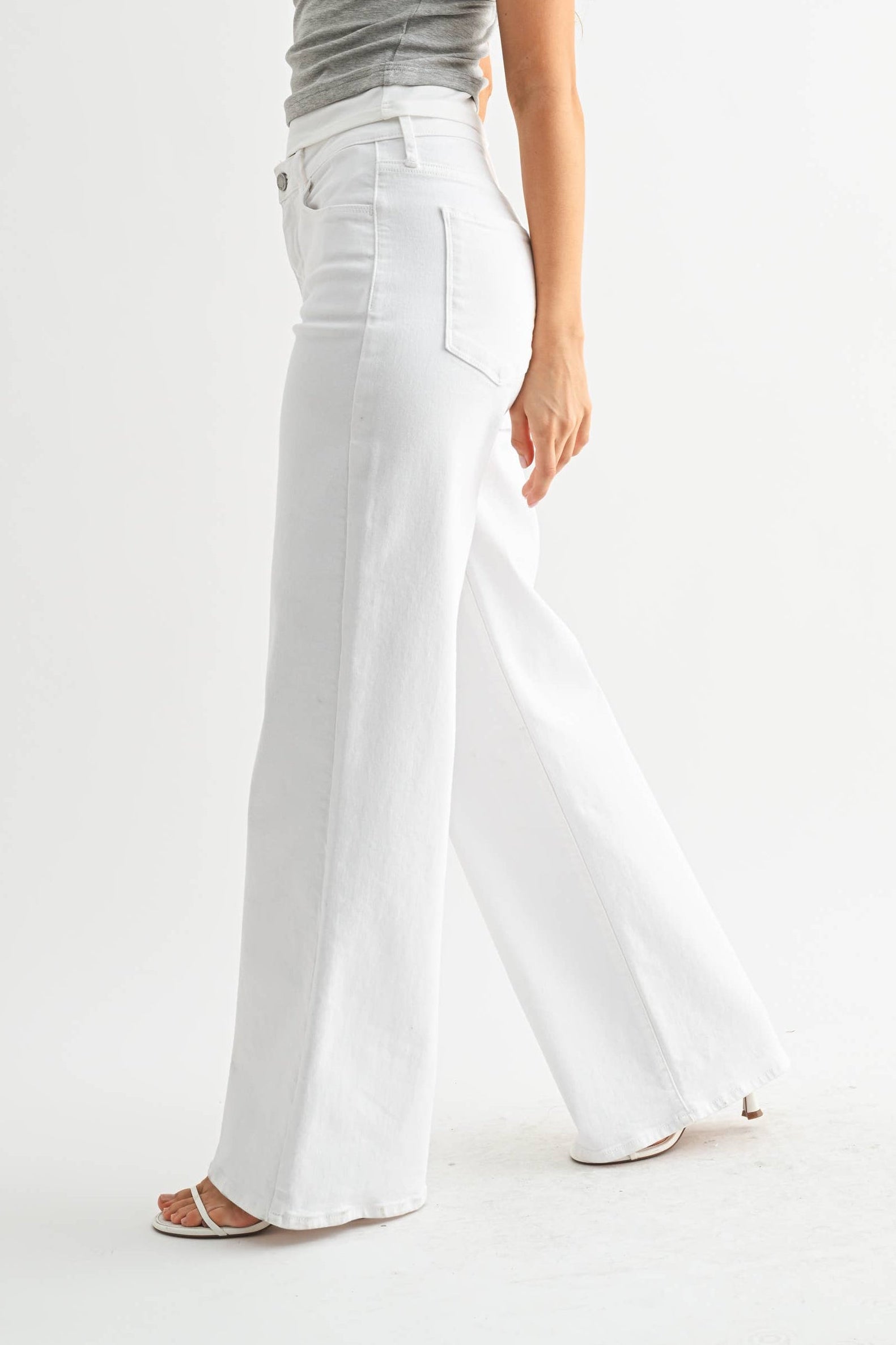 Woman wearing a gray t-shirt and white pants on a white background