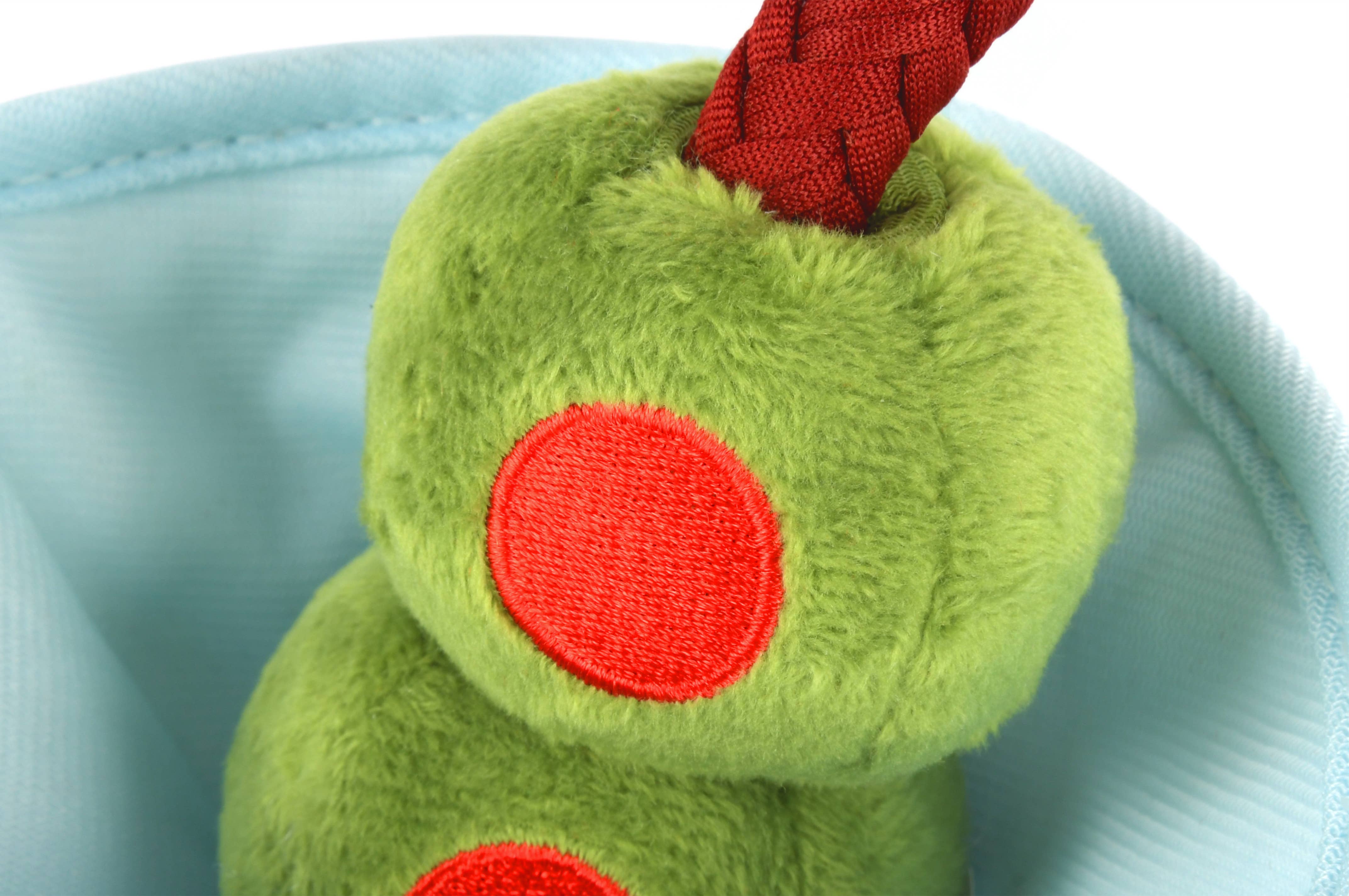 Green plush toy with red accents on a light blue background