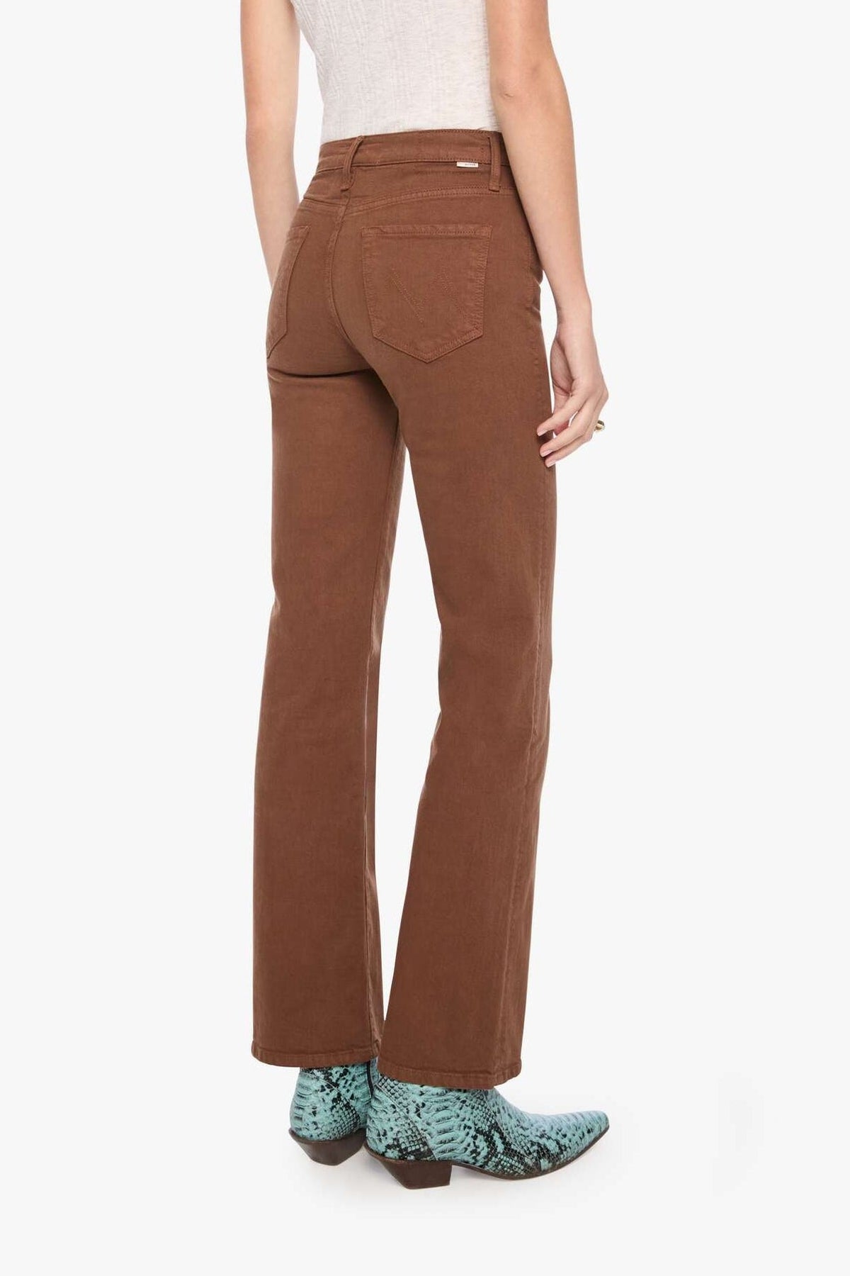 Woman wearing brown flared pants and a white top on a white background