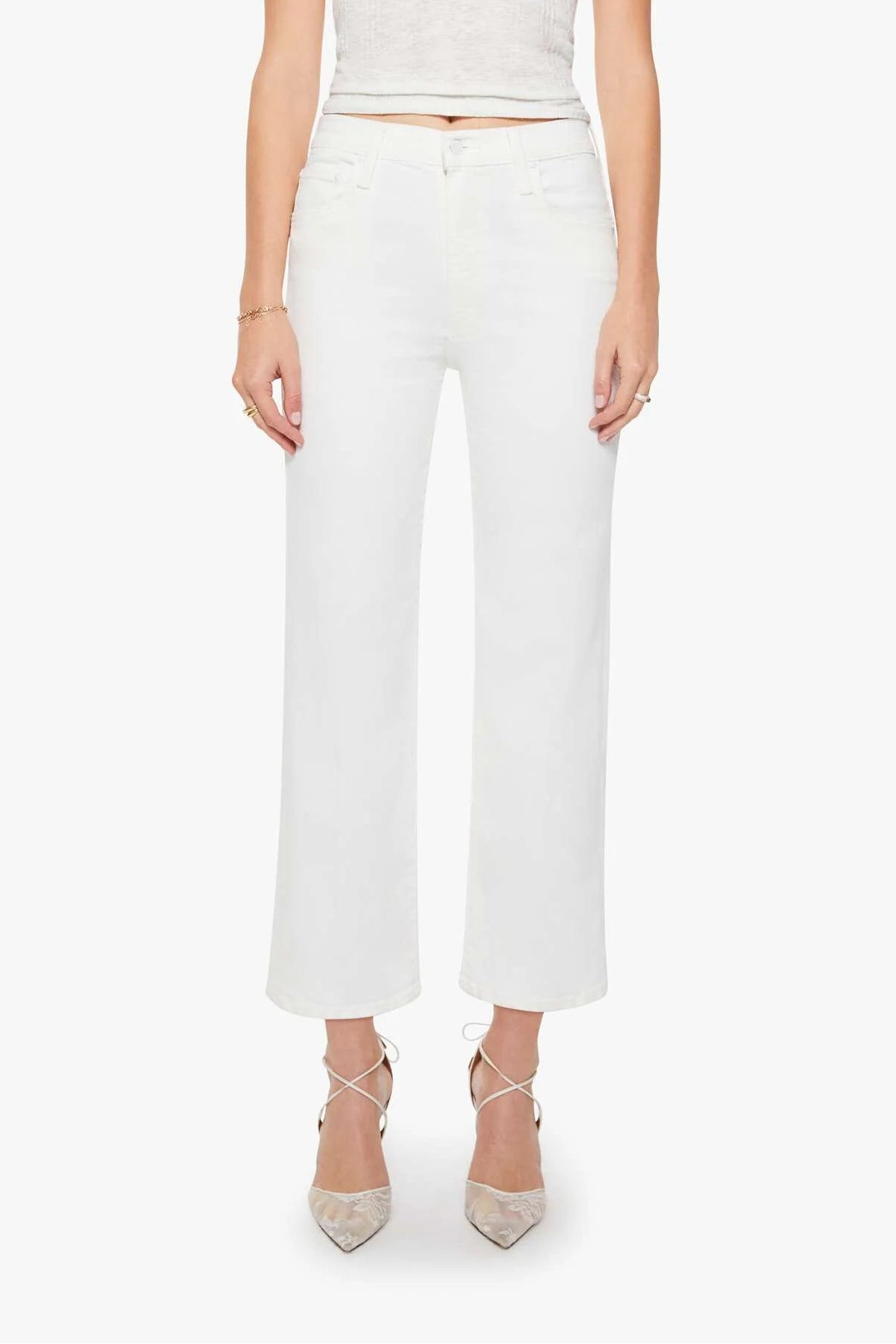A blonde model stands against a light gray studio background wearing a white short-sleeve cropped knit top, white wide-leg cropped pants, and beige pointed-toe heels.