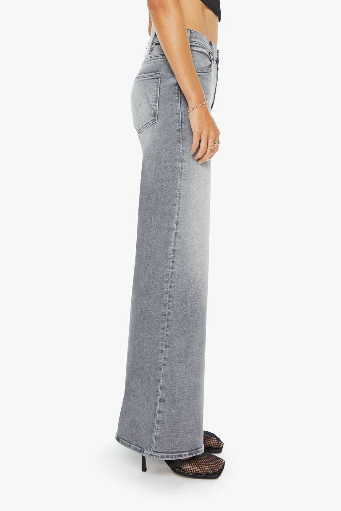 Woman wearing a black top and light gray flared jeans on a white background