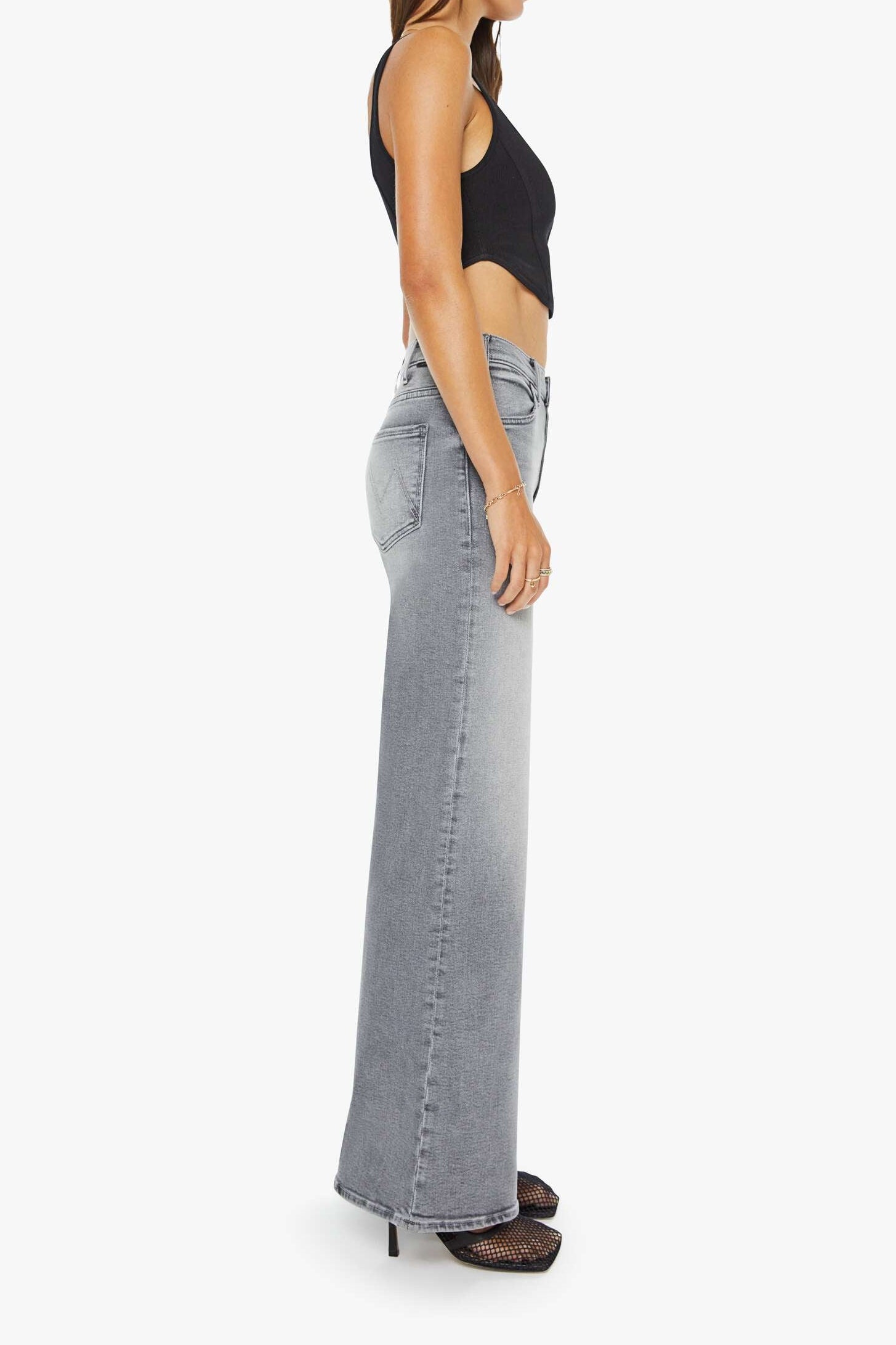 Woman wearing a black top and light gray flared jeans on a white background