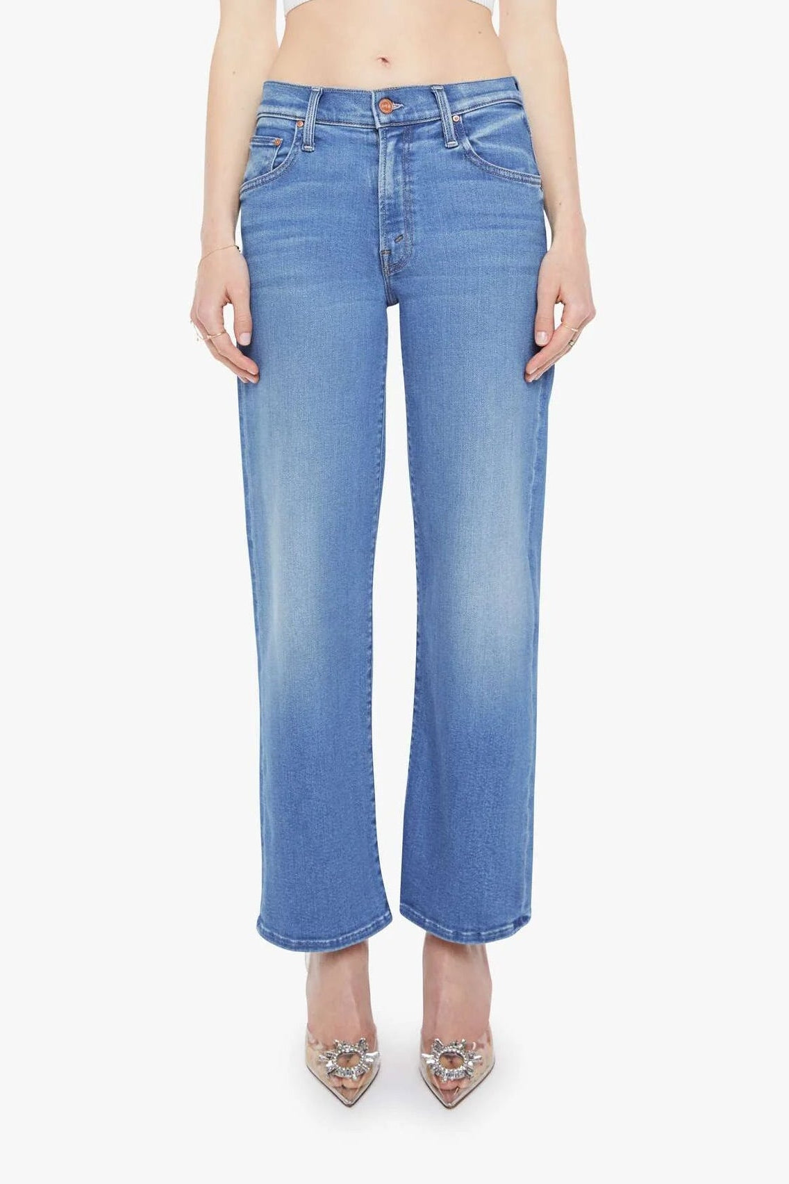 Woman wearing a white crop top and blue jeans on a white background