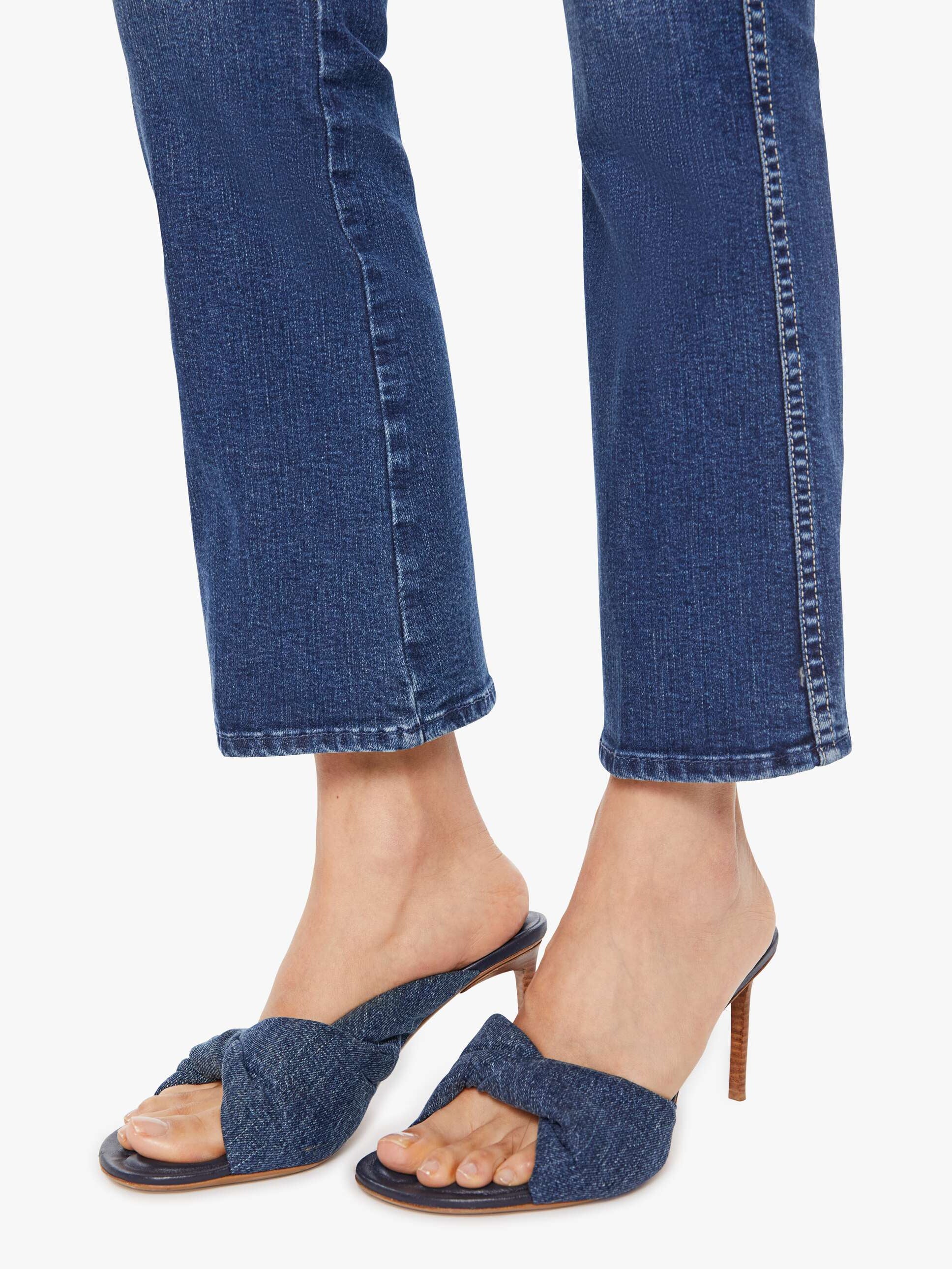 Denim sandals worn with blue jeans on a white background