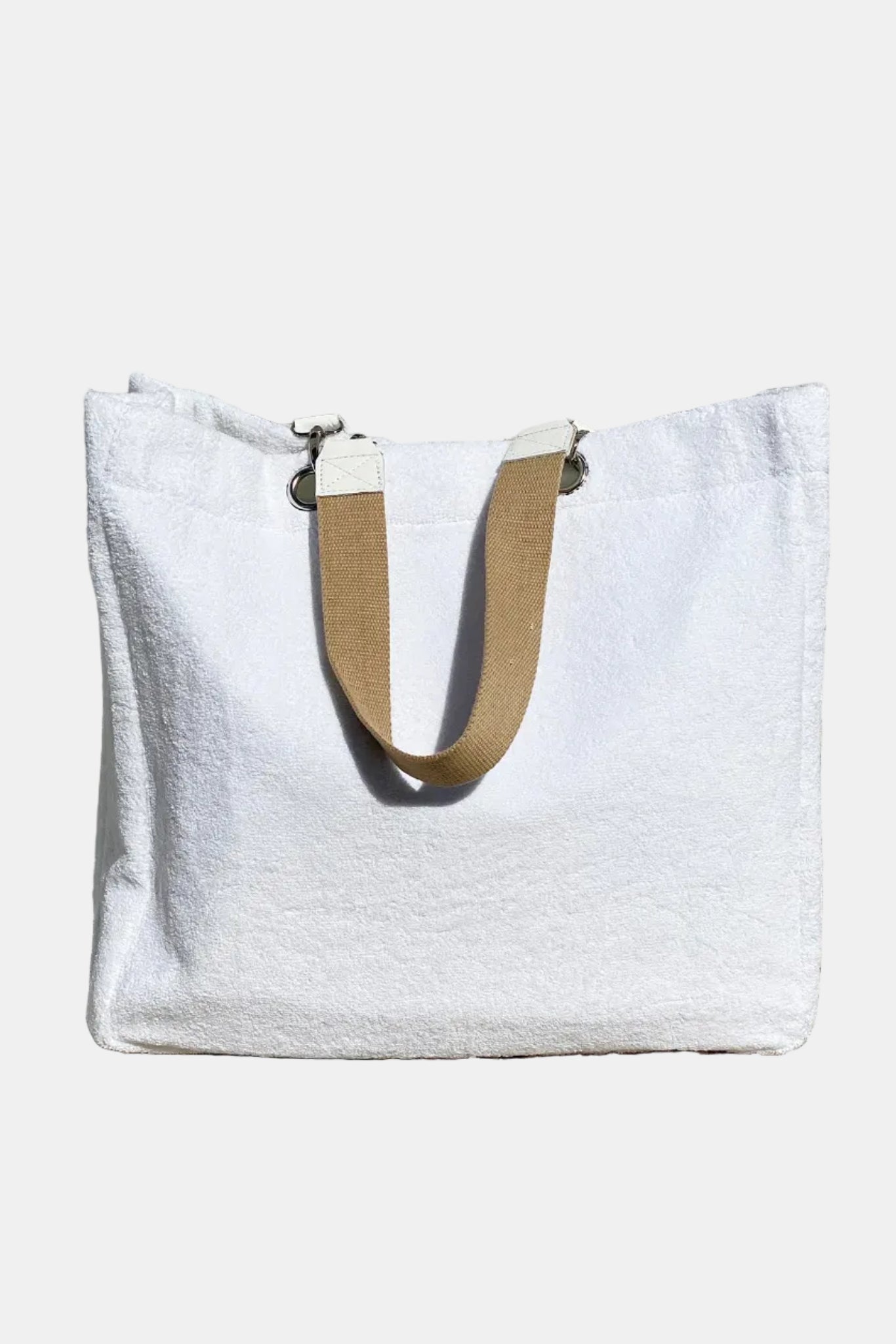 White tote bag with a beige handle on a stone surface and stone wall background