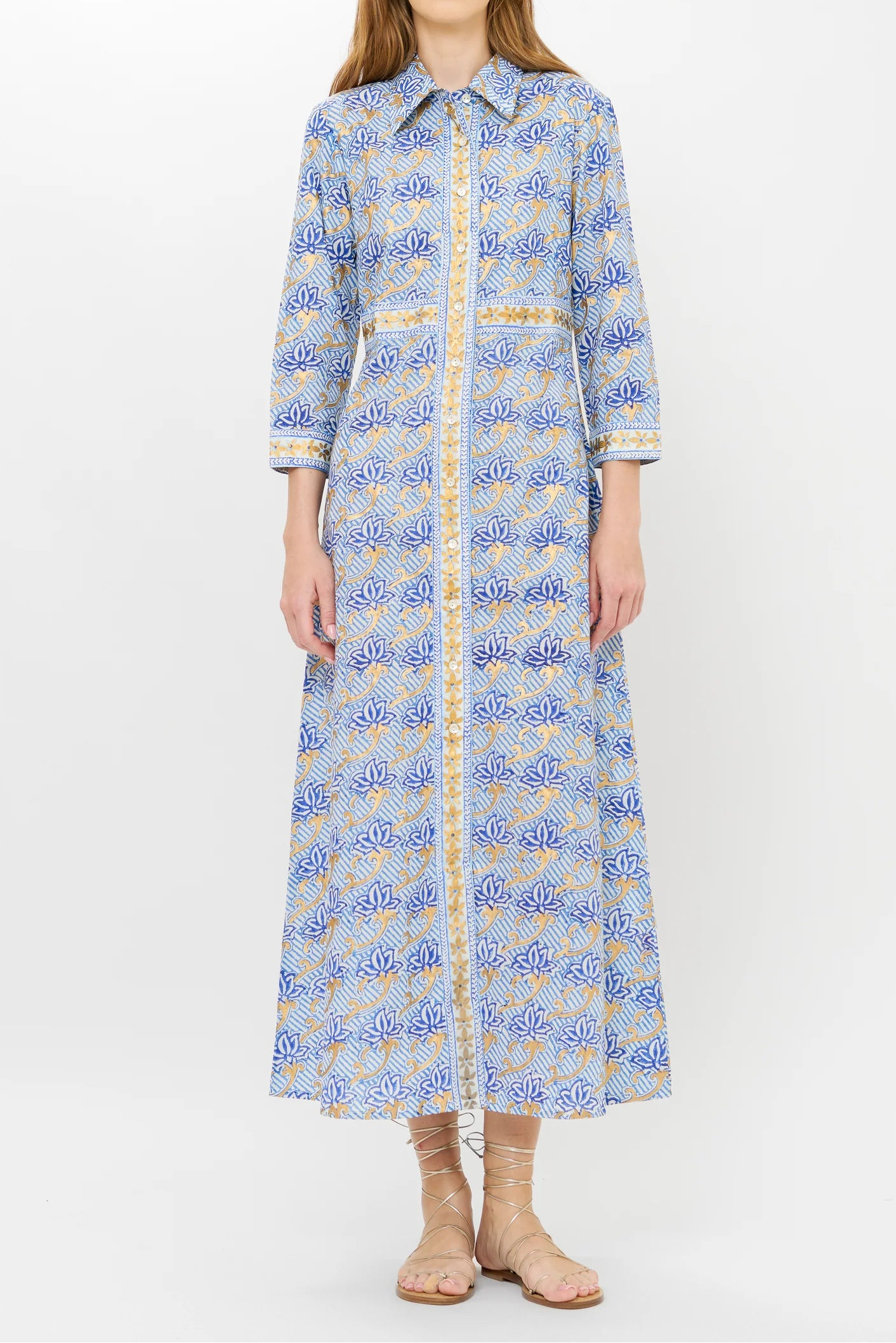 Woman wearing a long blue patterned dress on a white background