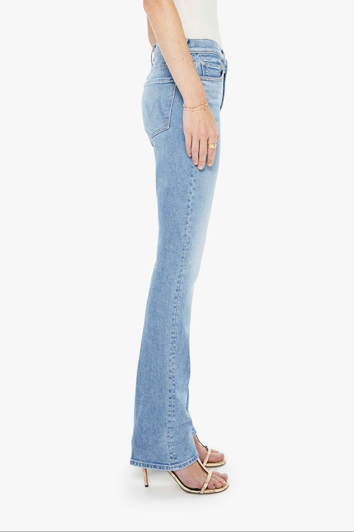 Woman wearing light blue flared jeans and a white top on a white background