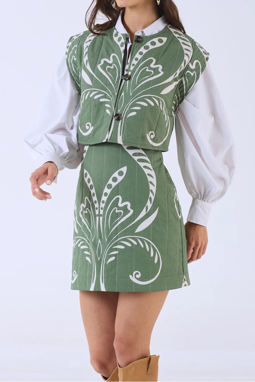 Woman wearing a green patterned outfit on a white background