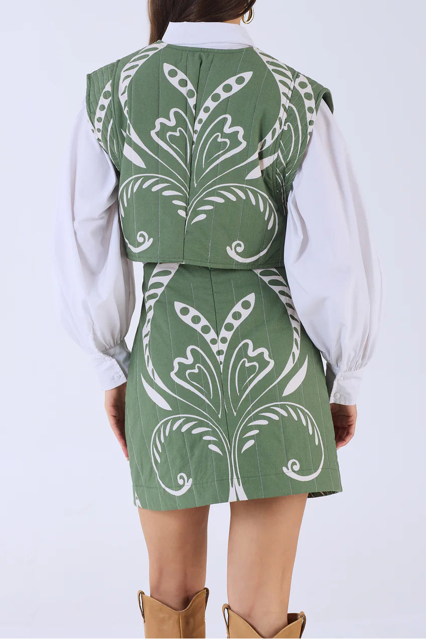 Person wearing a green patterned vest over a white shirt on a white background