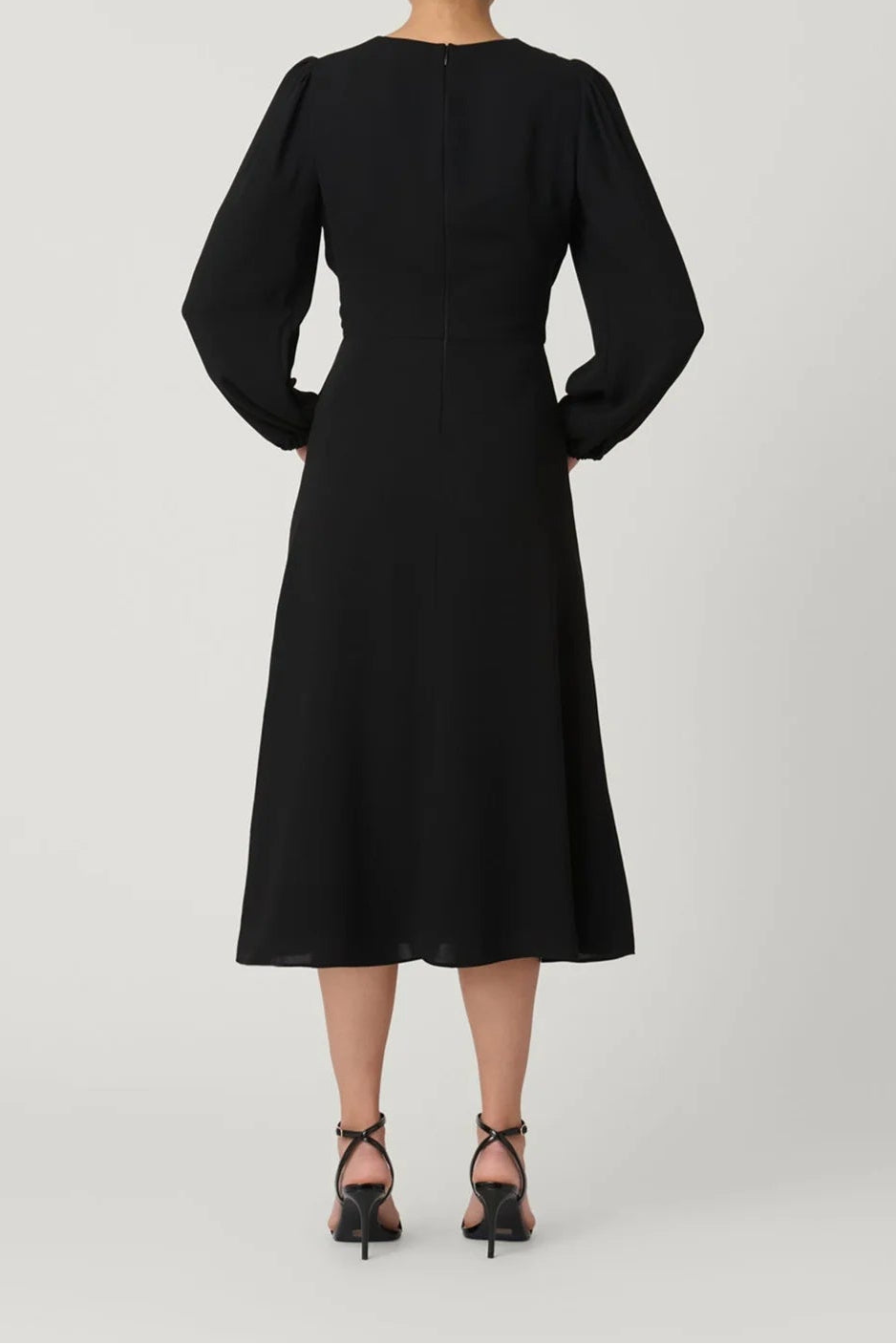 Woman wearing a black dress with long sleeves on a white background