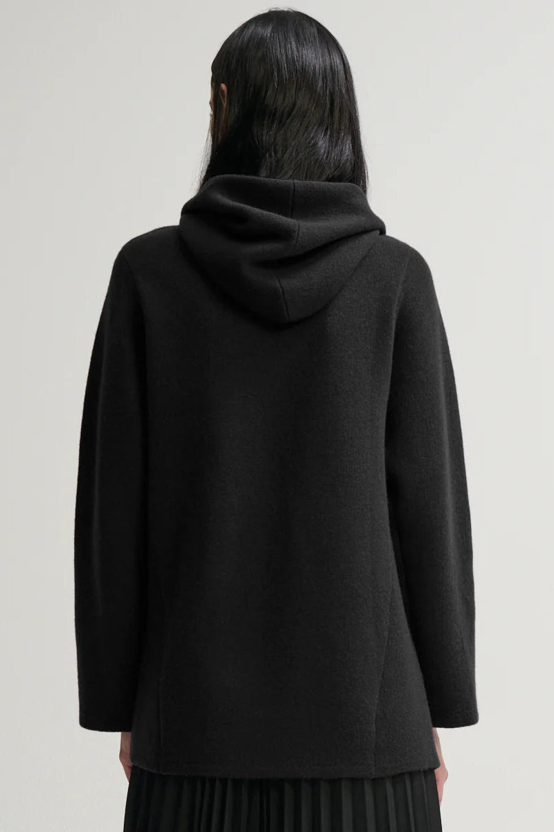 Person wearing a black hoodie from behind on a plain background