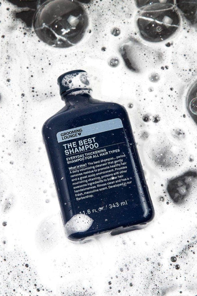 Bottle of 'The Best Shampoo' surrounded by bubbles on a textured surface