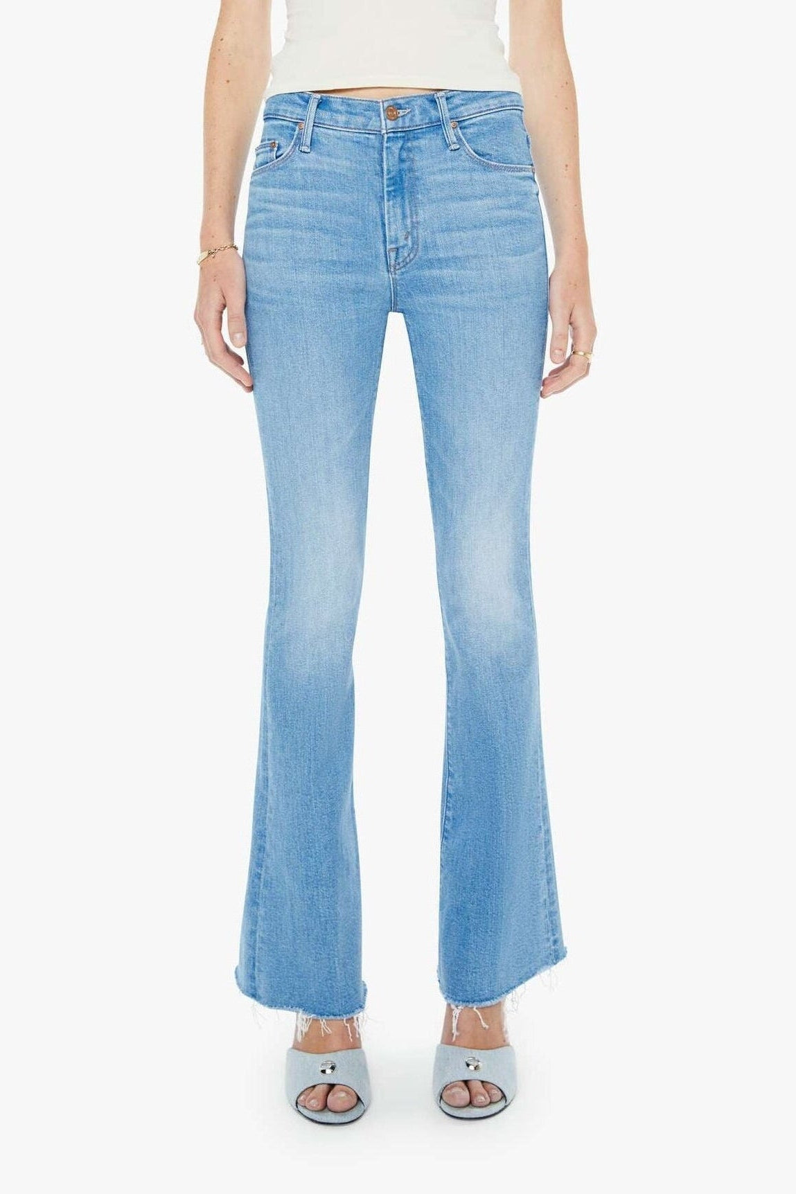 Woman wearing light blue jeans and a white top on a white background