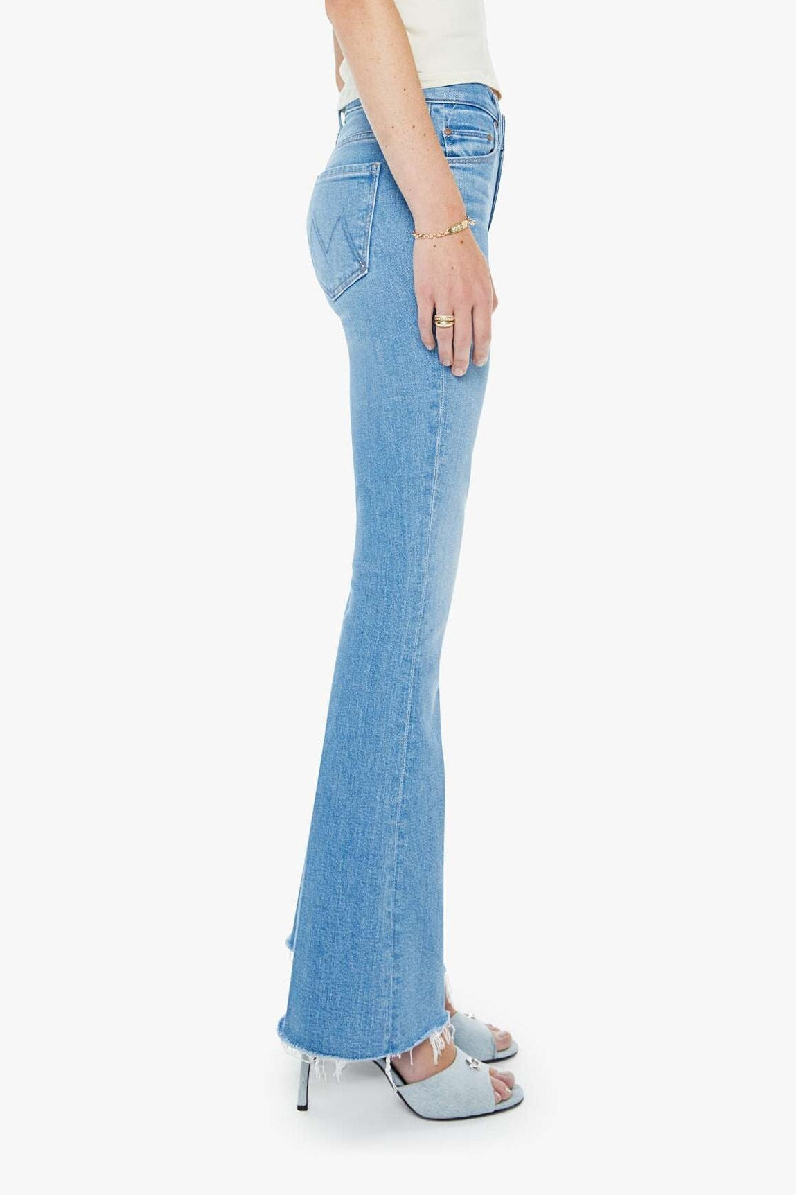 Woman wearing light blue flared jeans and a white top on a white background