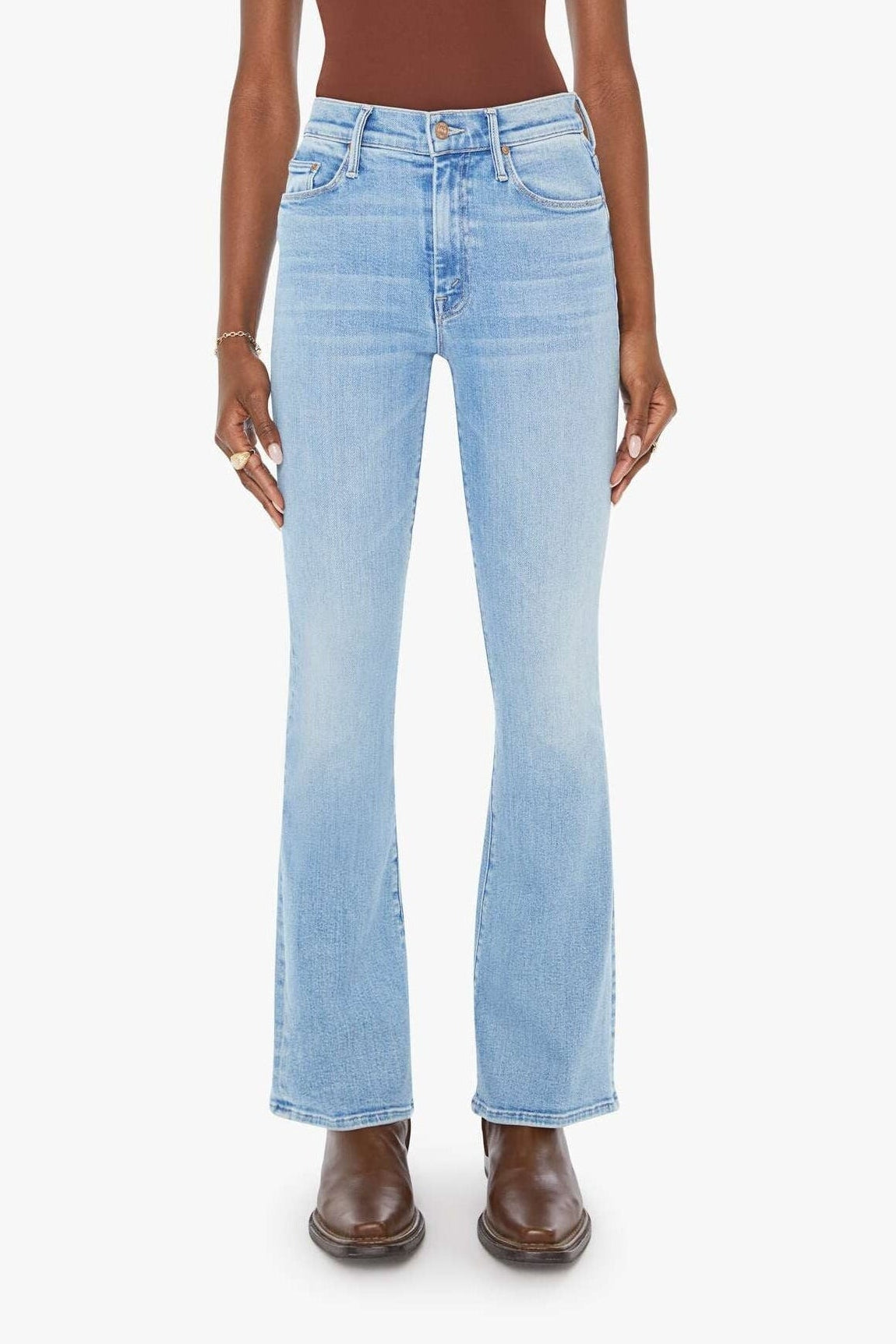 Woman wearing a brown tank top and light blue jeans on a white background