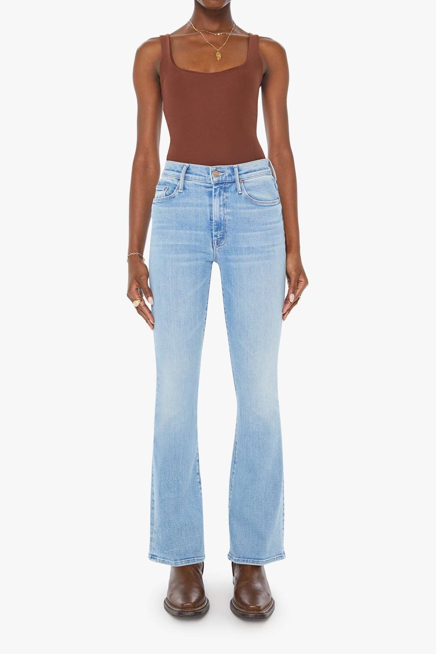 Woman wearing a brown tank top and light blue jeans on a white background