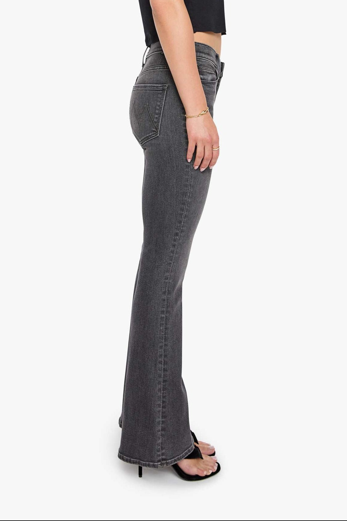 Woman wearing black top and gray flared jeans on a white background