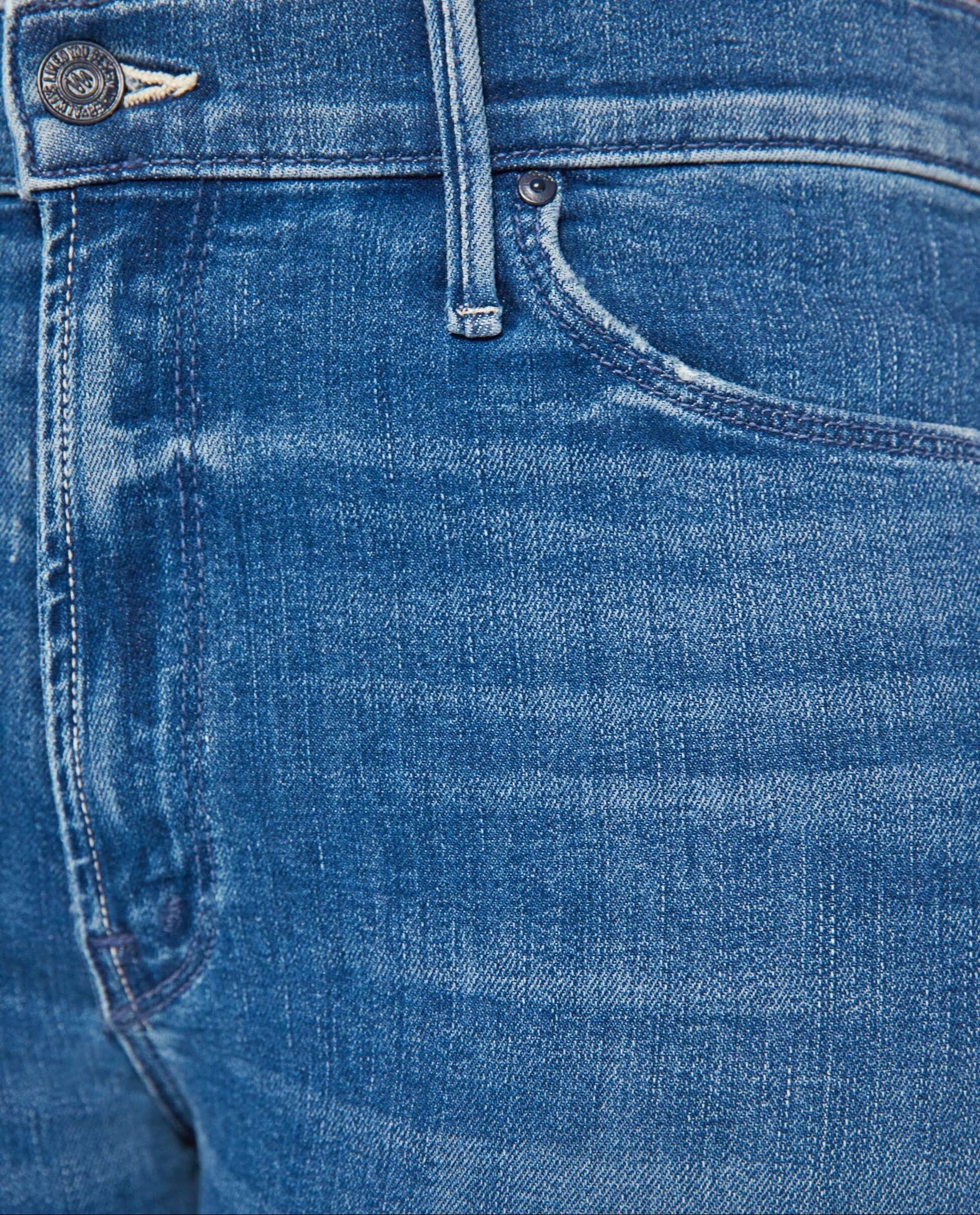 Close-up of blue denim jeans showing the waistband, button, belt loops, front pocket, and fabric texture.