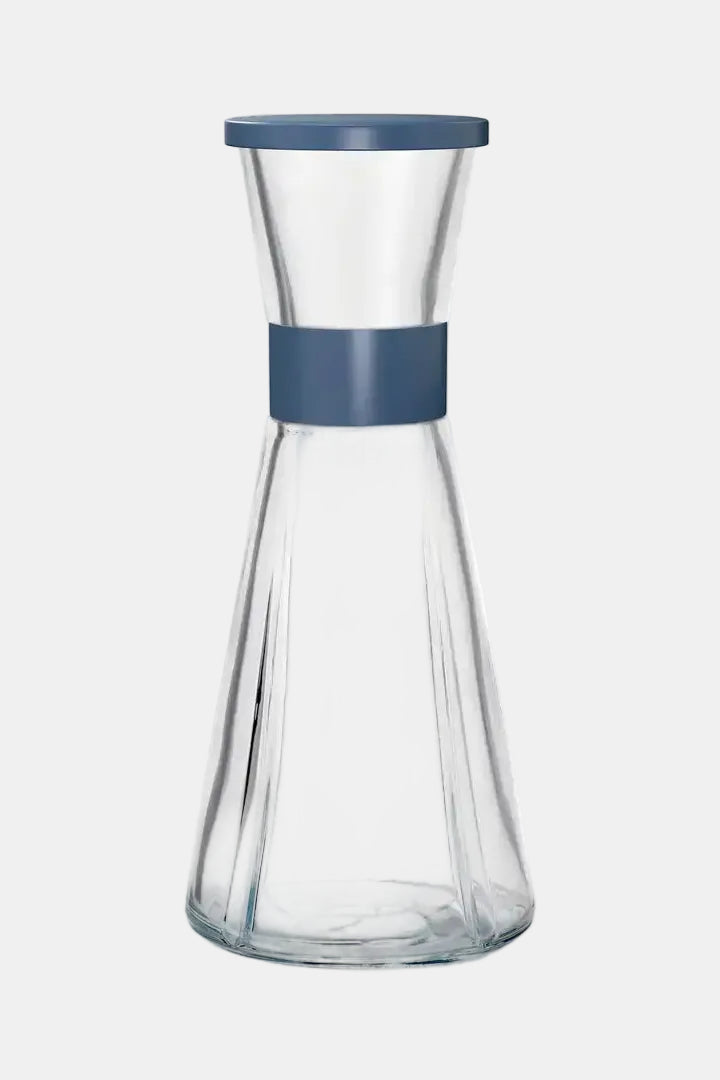 Clear glass carafe with blue band and lid on a white background
