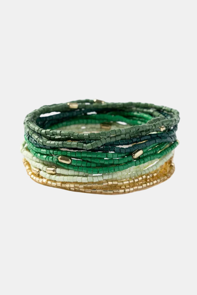 Set of green, gold, and white beaded bracelets on a white background