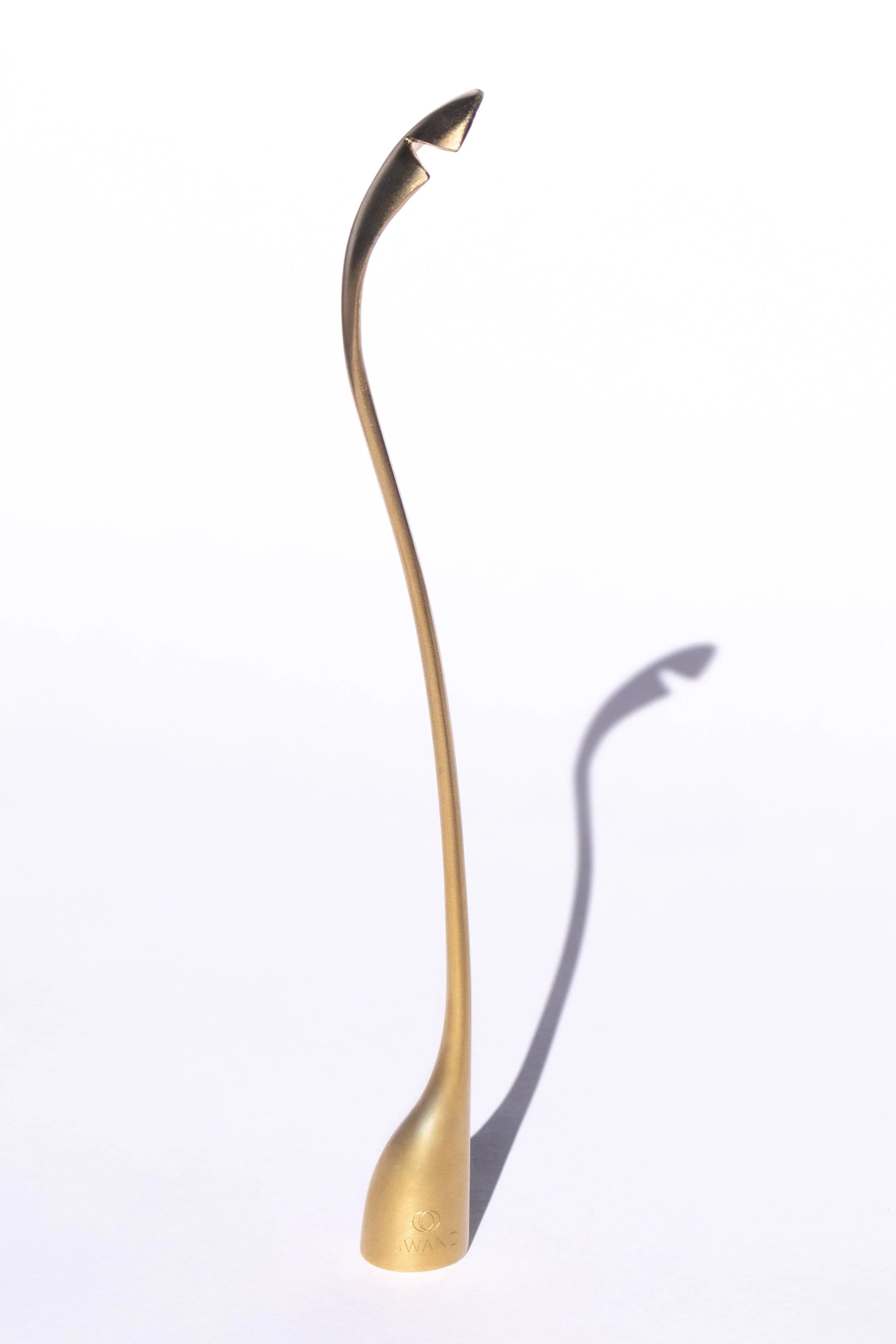 A modern, sculptural lamp with a curved, snake-like stem and a pointed, leaf-like top, finished in a brushed gold metal, shown on a white background with a soft shadow.