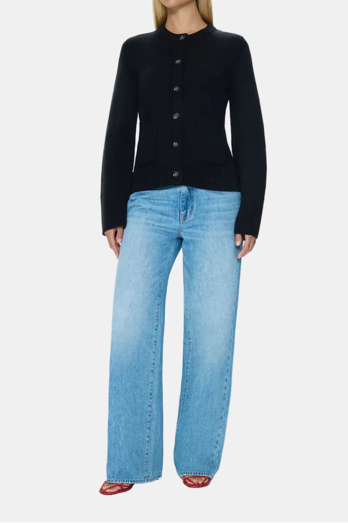 Woman wearing a black cardigan and light blue jeans on a white background
