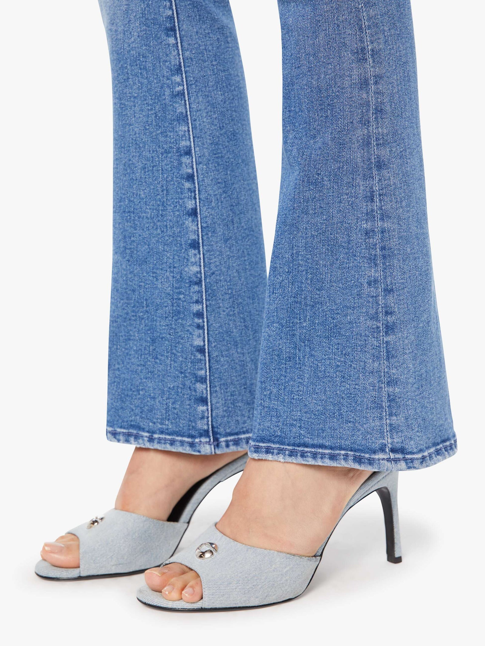 Gray high-heeled shoes worn with blue jeans on a white background