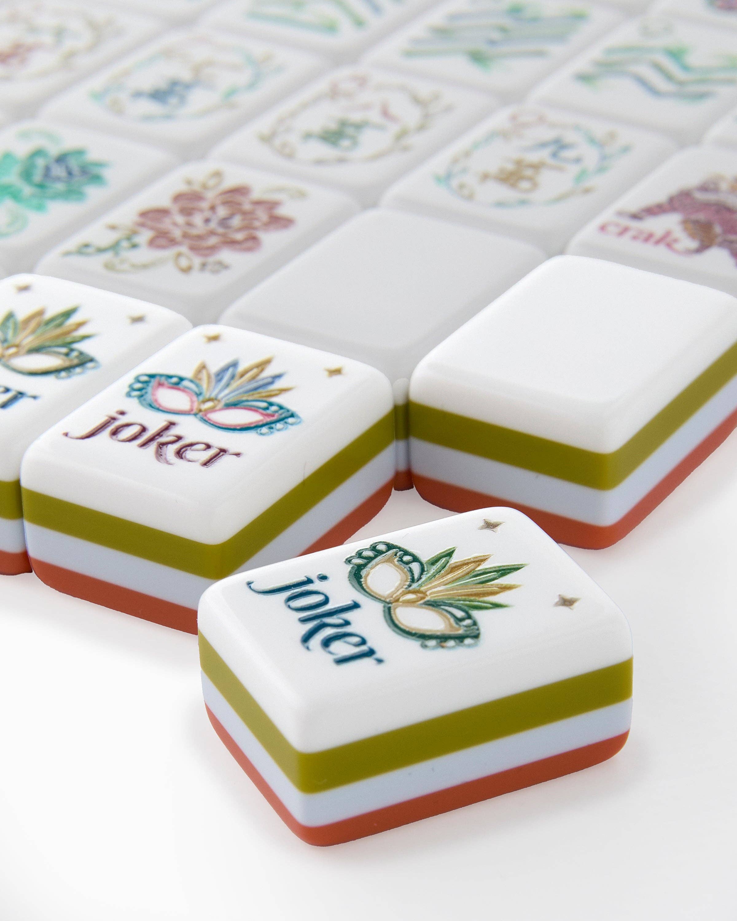 Close-up of decorative tiles with 'joker' and floral designs on a white surface.