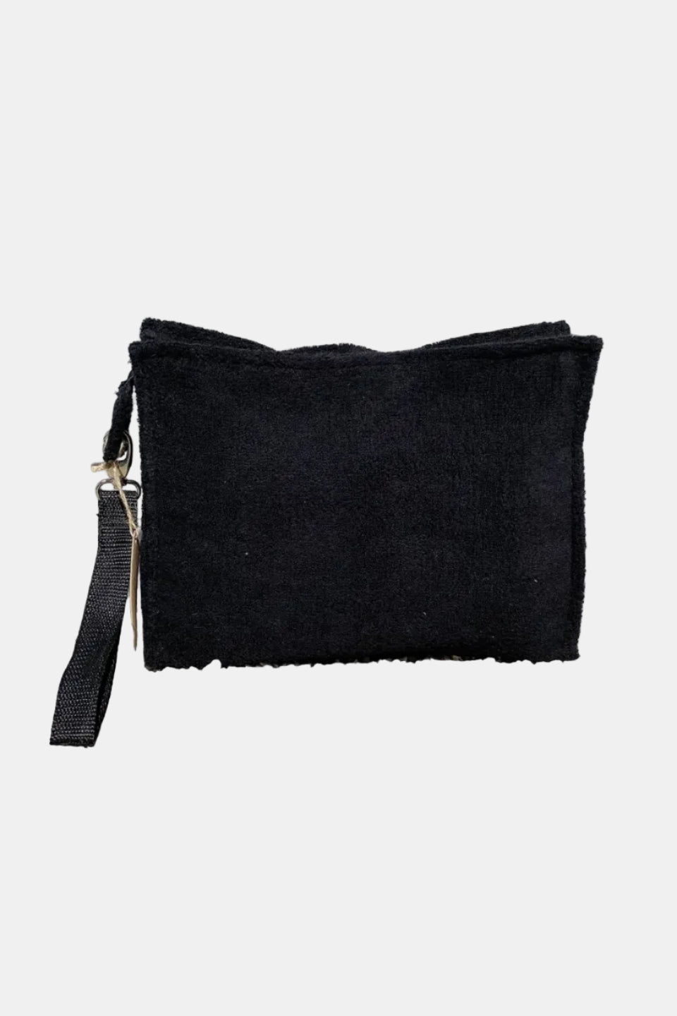 Black clutch bag with a strap on a stone surface with a light gray brick wall background
