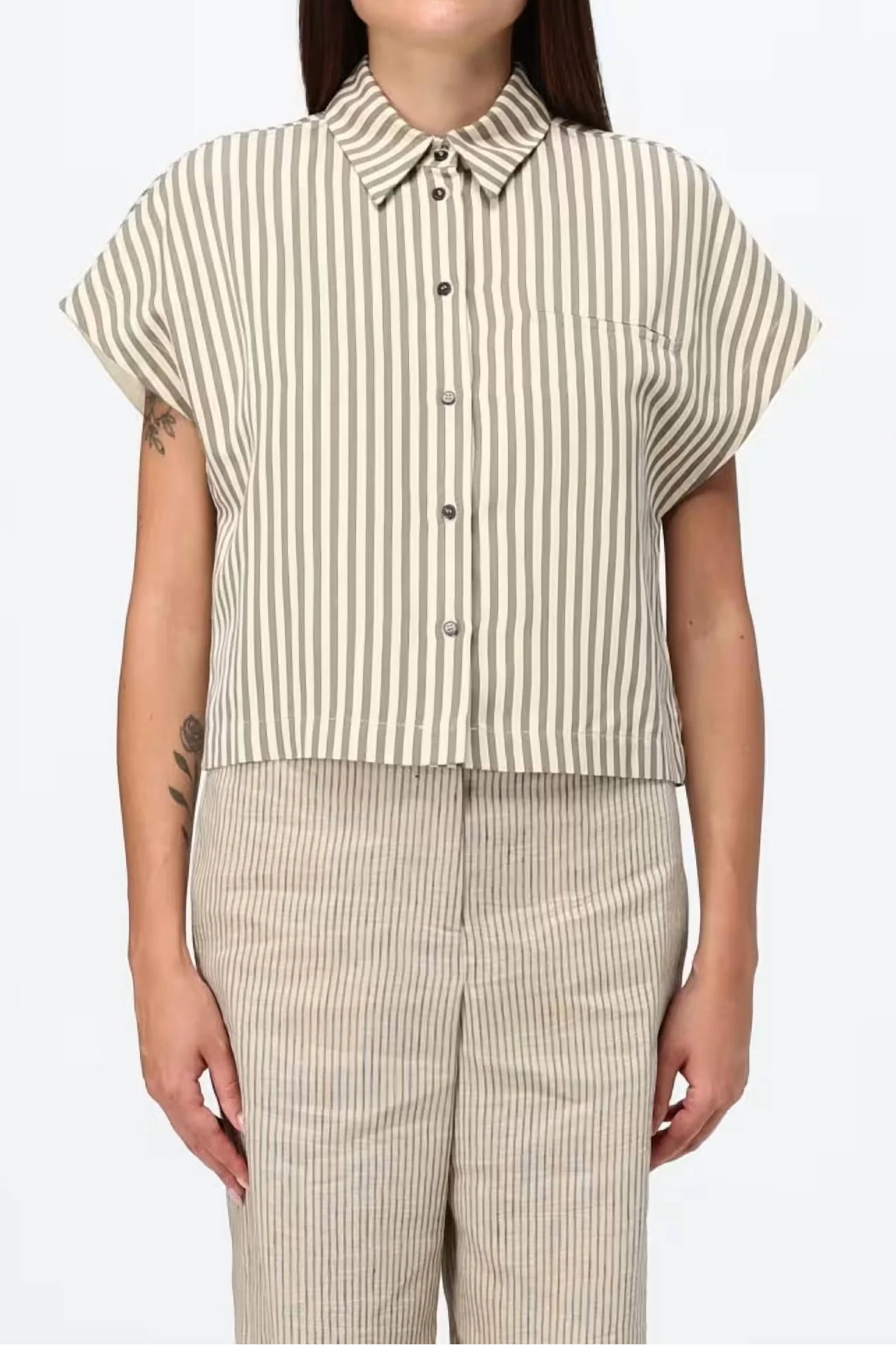 A model wearing a short-sleeve button-up shirt with vertical beige and white stripes, paired with matching striped trousers, against a plain white background.