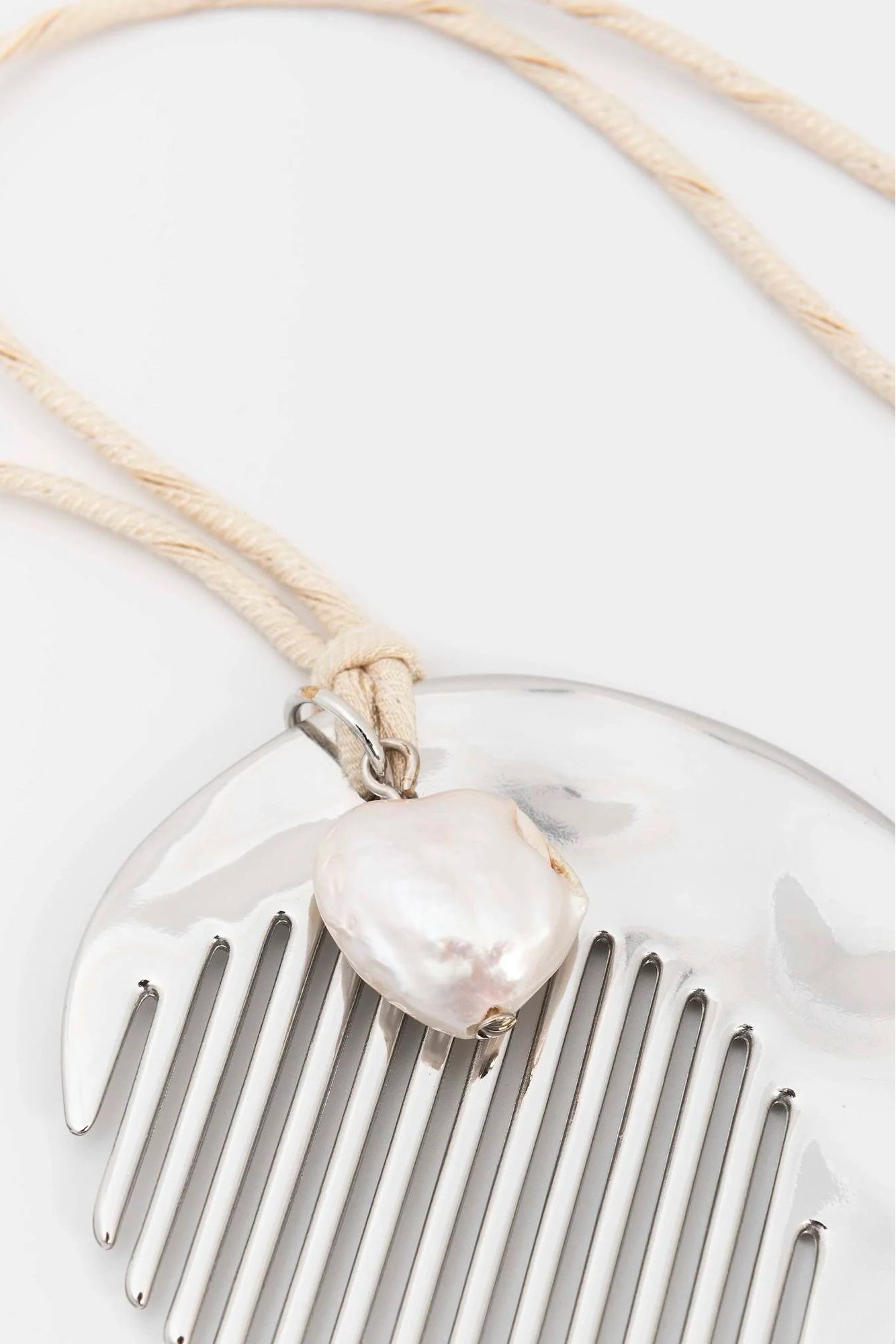 Silver comb with a pearl-like bead on a white background
