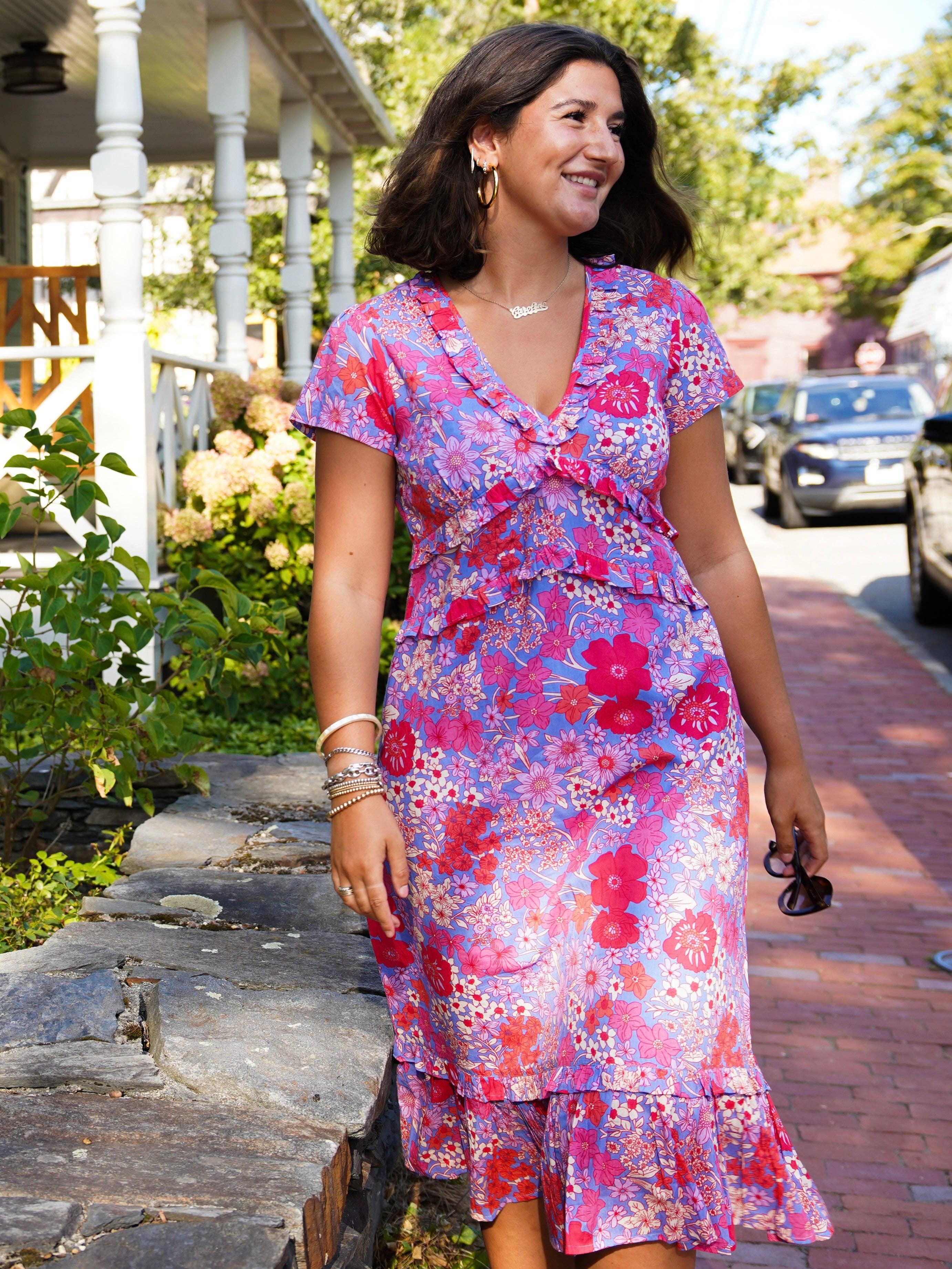 Woman wearing a colorful floral dress standing outdoors.