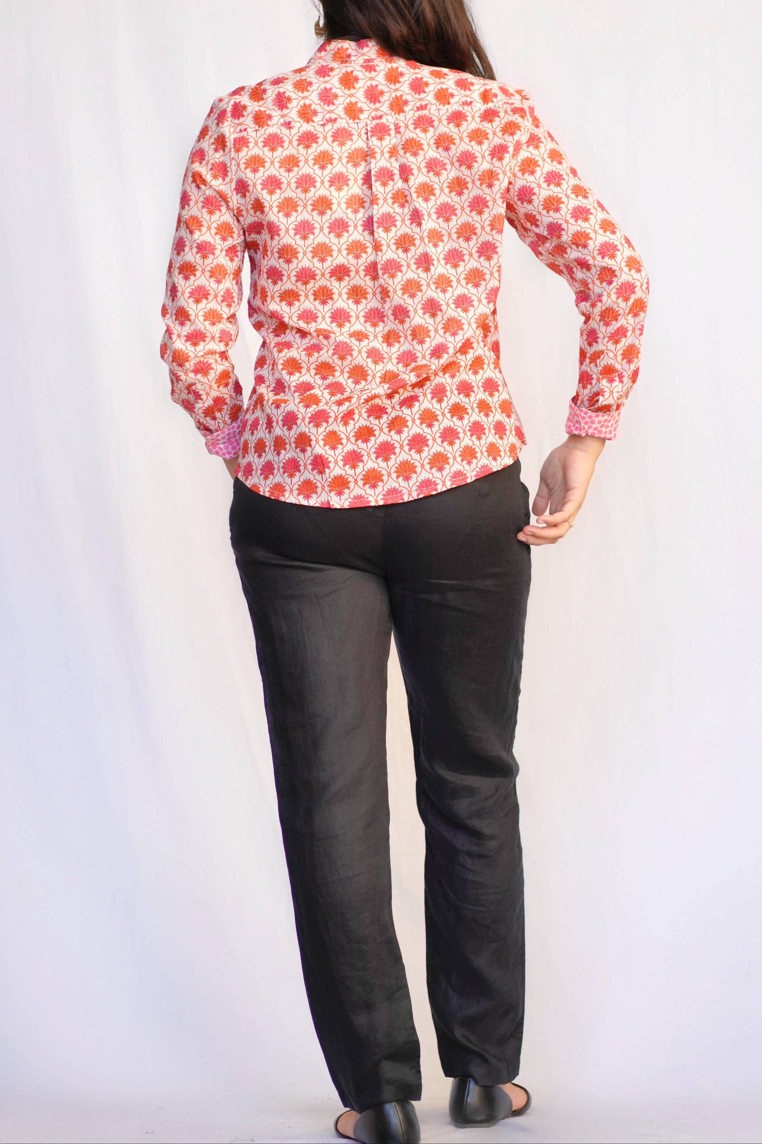 Person wearing a floral shirt and black pants on a white background