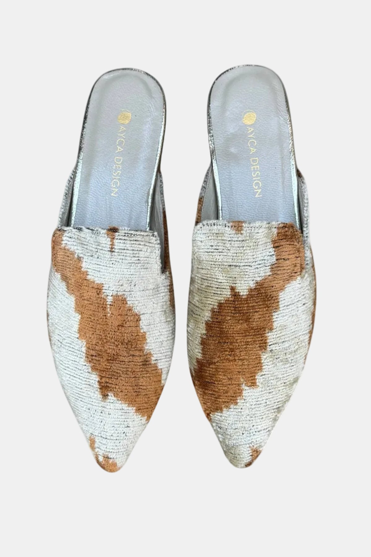 Pair of pointed-toe shoes with cow print pattern on a white background