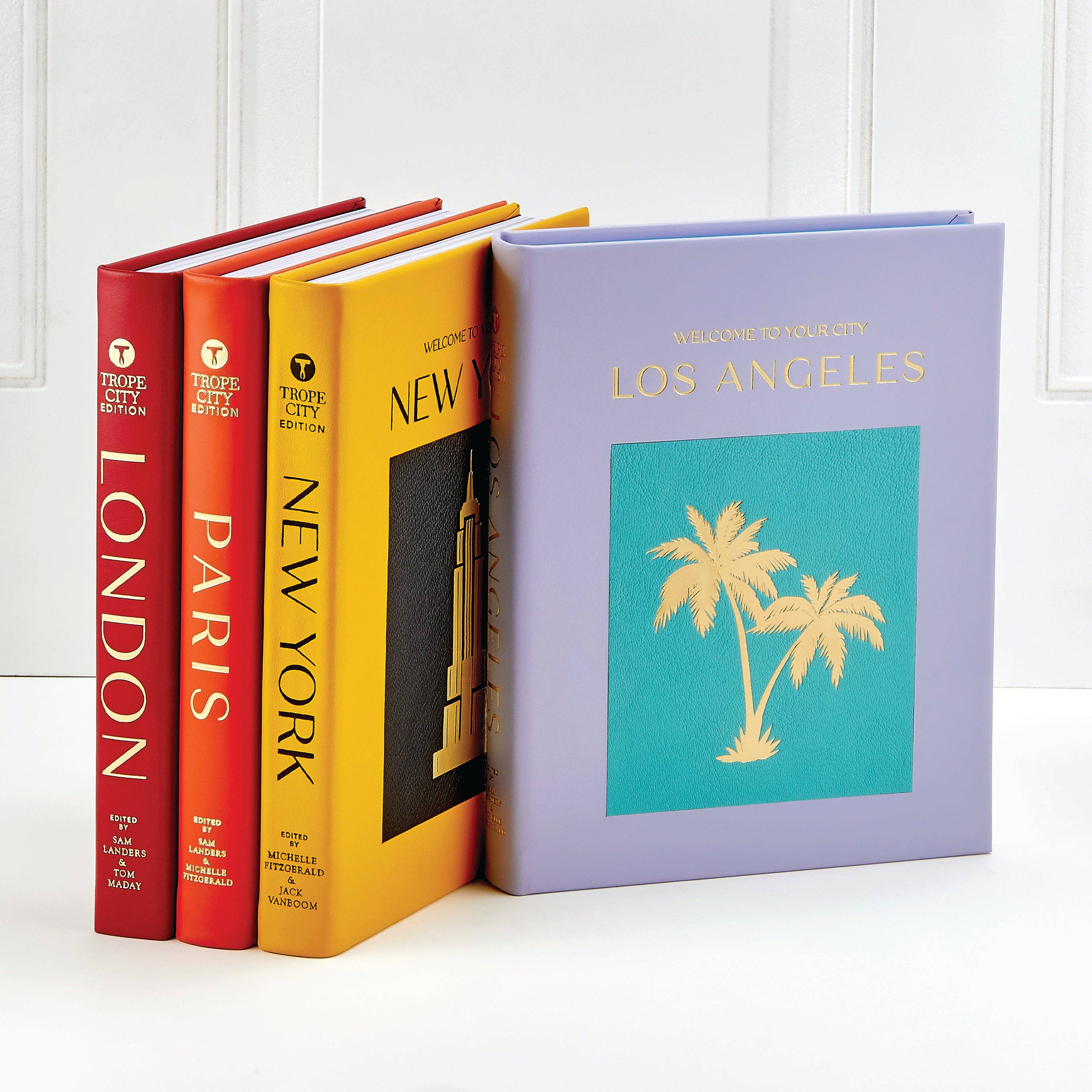 Set of books titled 'London', 'Paris', 'New York', and 'Los Angeles' on a white surface.