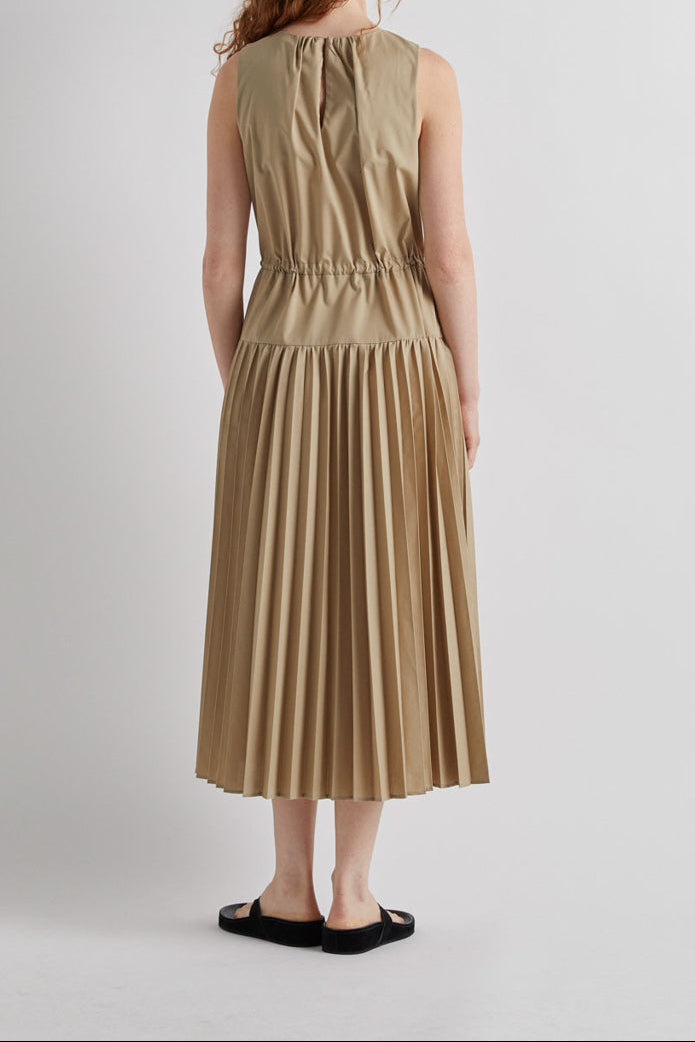 Woman wearing a beige pleated dress on a white background