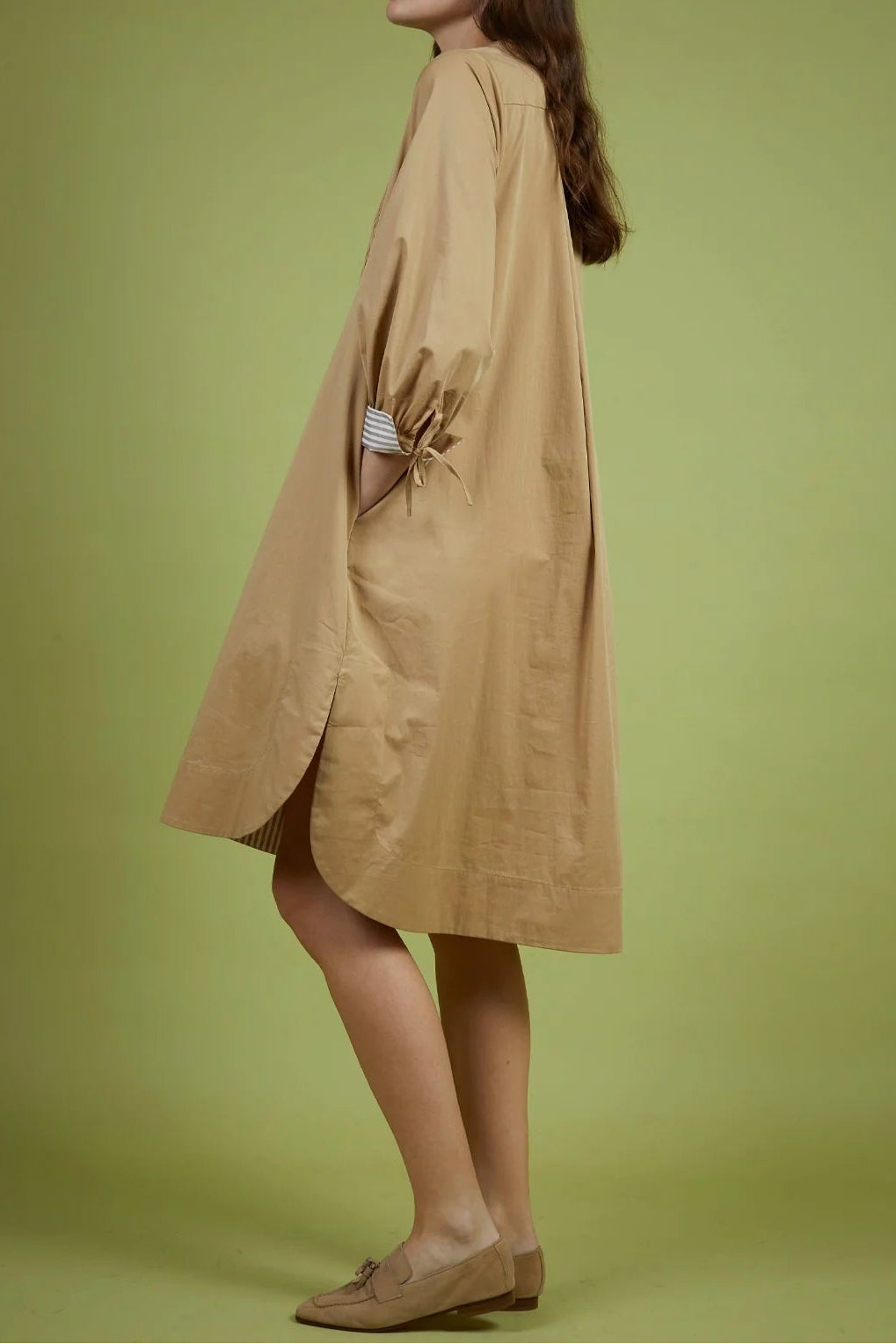 Woman wearing a beige coat against a green background