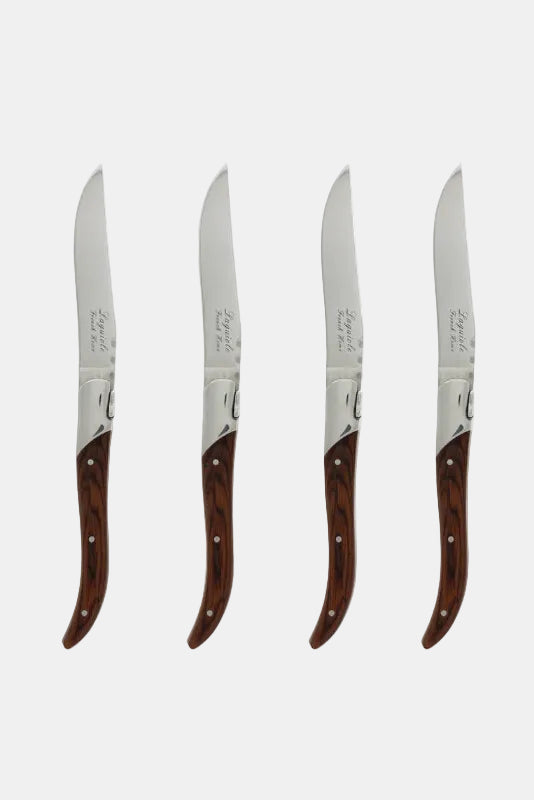 Set of four steak knives with wooden handles on a white background